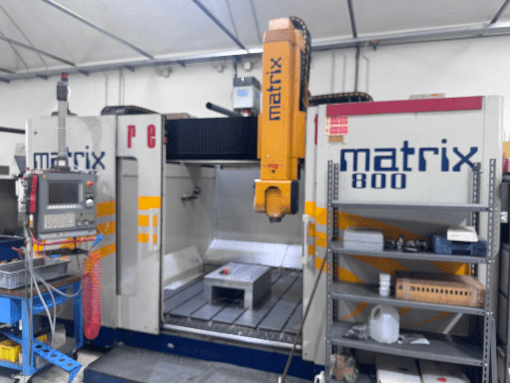 Matrix 800 CNC-tööpink töökoja vaates, kus on juhtpaneel, tööriistad ja töölaud koos erinevate objektidega.