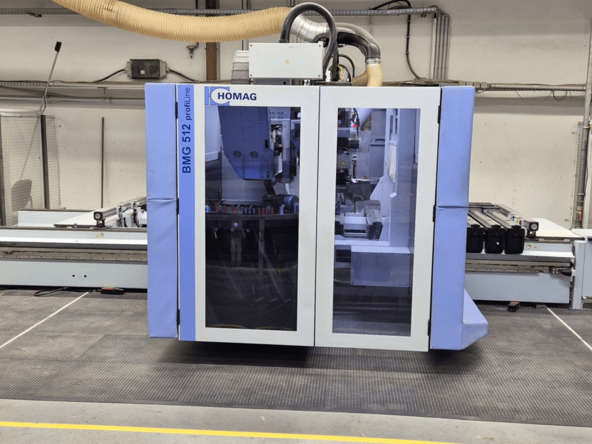 HOMAG BMG 512 ProfiLine CNC-tööpink, esivaade, klaasist paneel, täppistööriistad nähtavad ja tööstuslik seade.