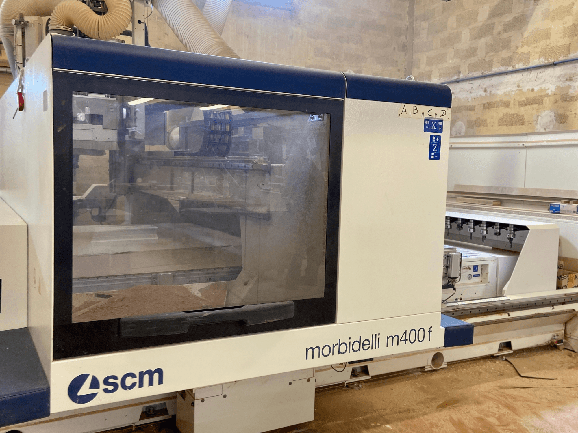 SCM Morbidelli M400F CNC-tööpink, esivaade, millel on juhtpaneel ja nähtav saepuru põrandal.