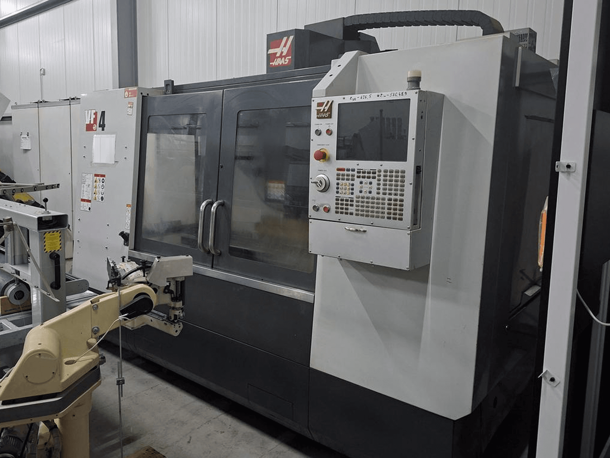 Haas VF-4 CNC-freesping eesvaates, millel on numbriline juhtpaneel ja robotkäsi automatiseerimiseks.
