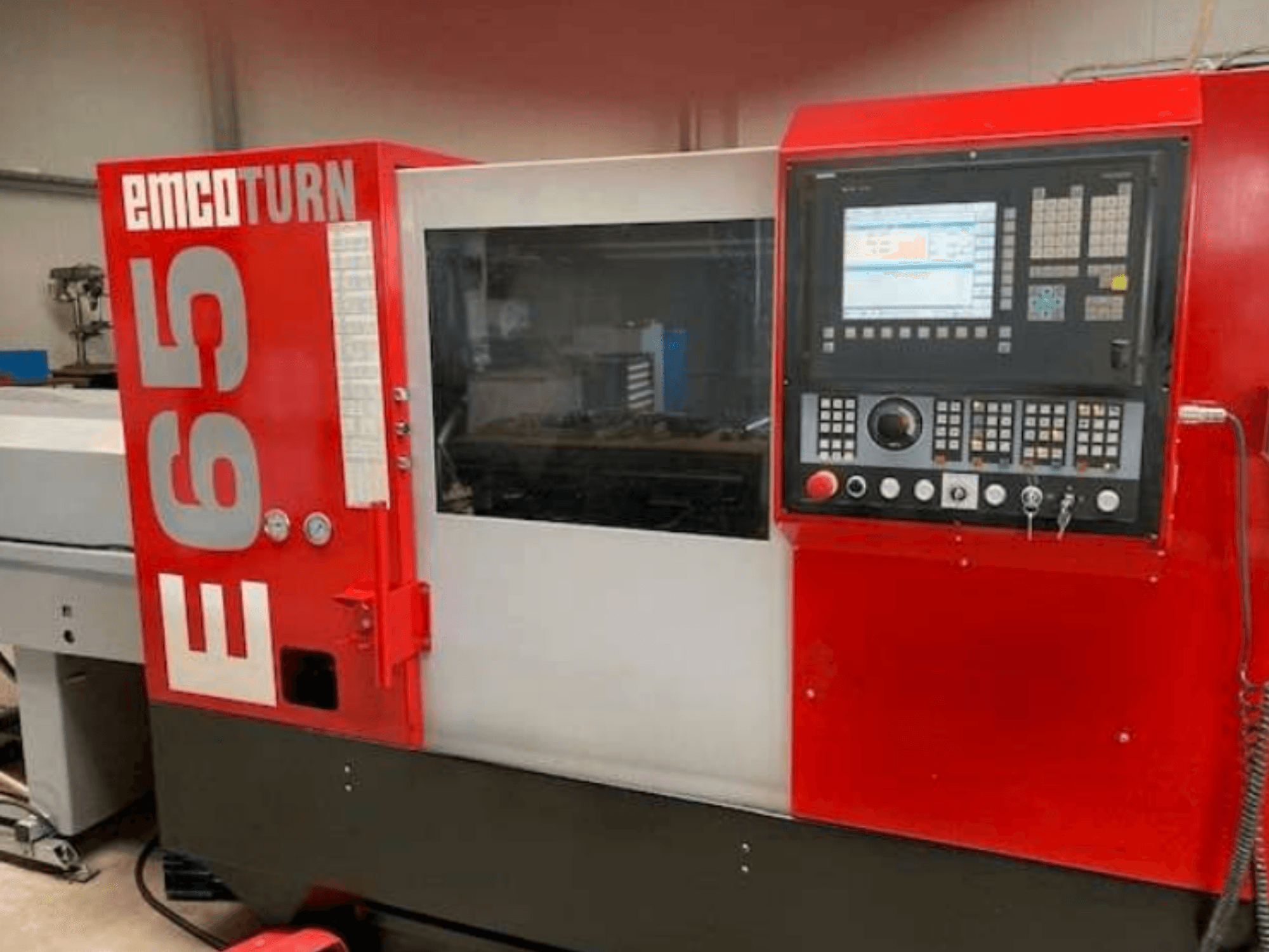 EMCO Turn E65 CNC-teeninduspingi esivaade, kus on näidatud juhtpaneel, suur ekraan ja tööala klaasi taga.