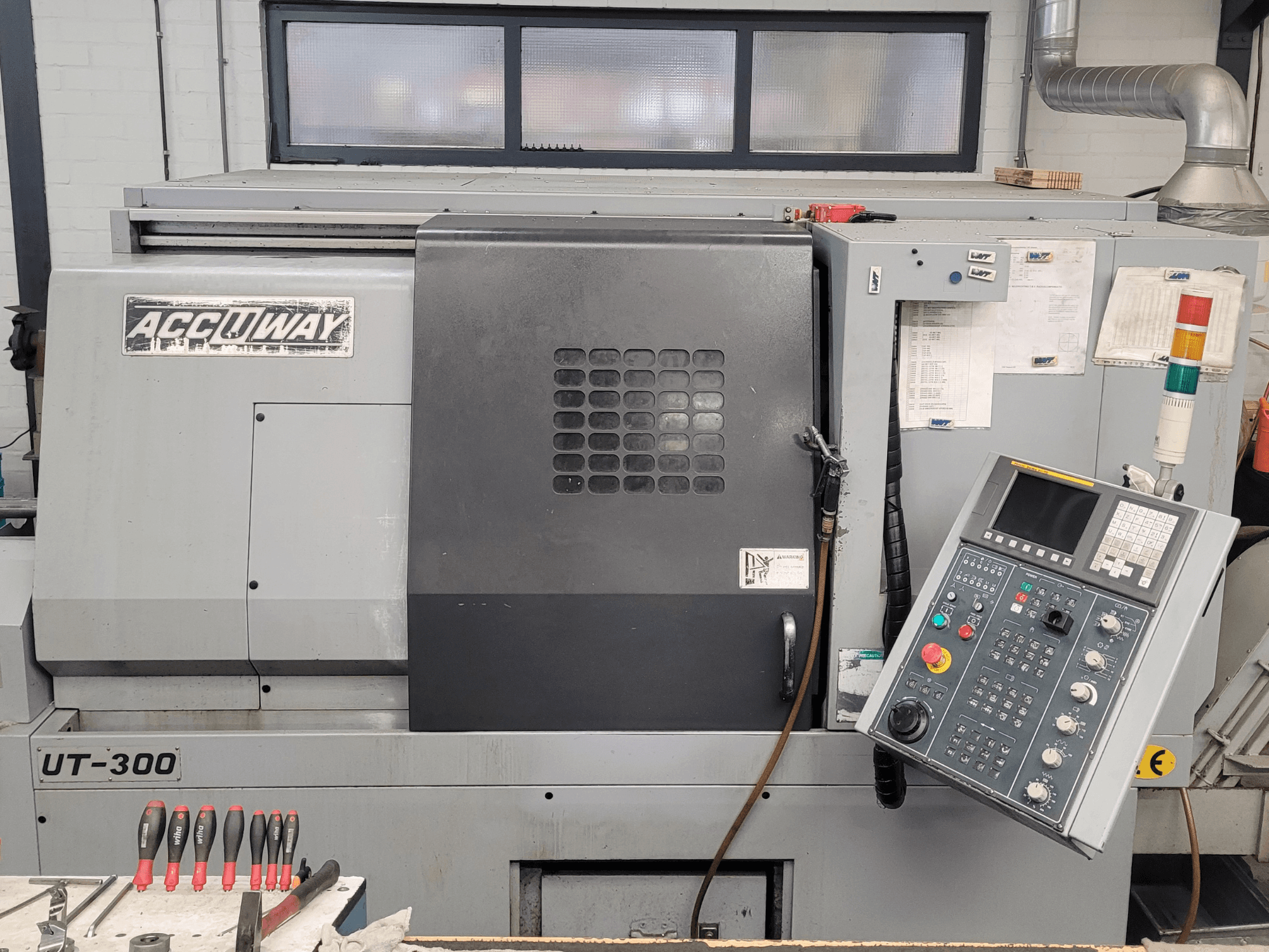 Accuway UT-300 CNC-tööpink eesvaates, millel on juhtpaneel ja mitmesugused juhtimisnupud, töökojas.