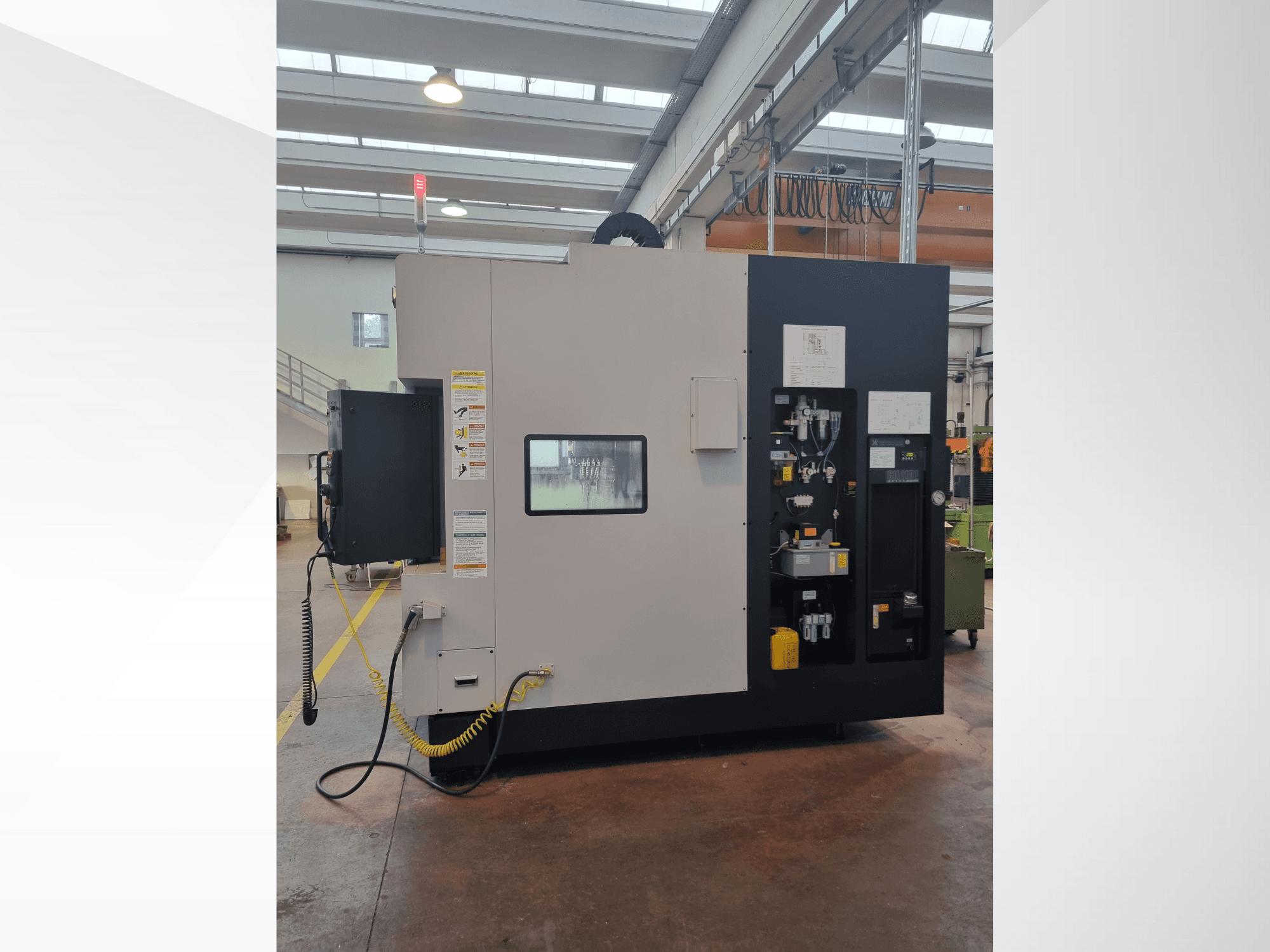 Tööstusmasin külgvaates, millel on juhtpaneel nuppude, näitajate ja ohutushoiatussildiga.