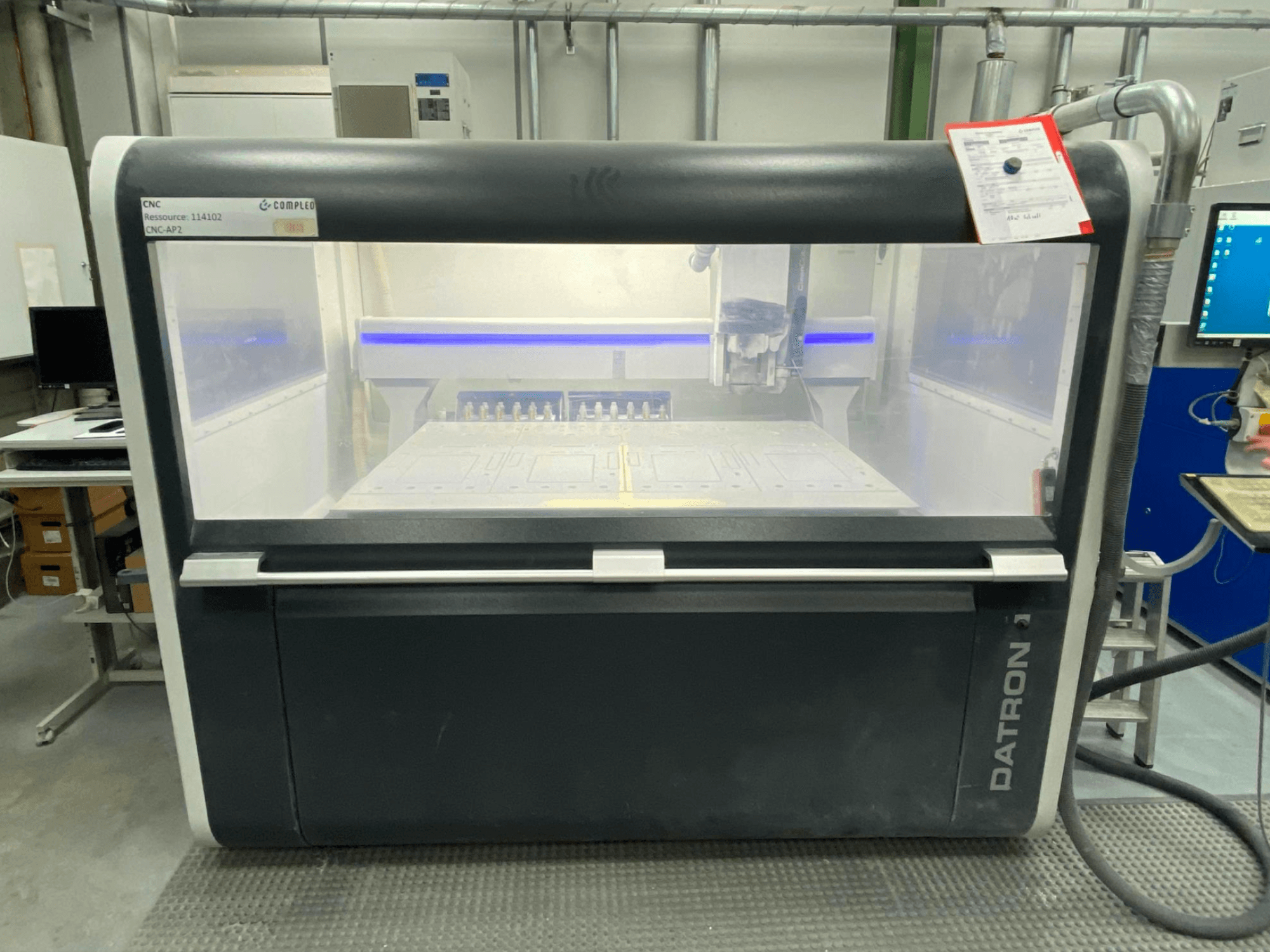 Datron MLCube B vertikaaltöötluskeskuse esiplaan, millel on nähtavad juhtimisseadmed ja töölaud töökojas.