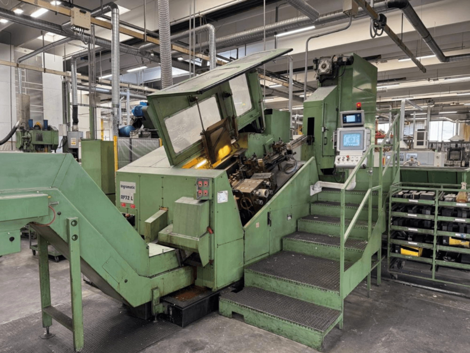 Ingramatic RP72 L, tööstuslik masin rohelises toonis, esiplaanil; juhtpaneel ja astmed koos metallrestiga platvormiga.