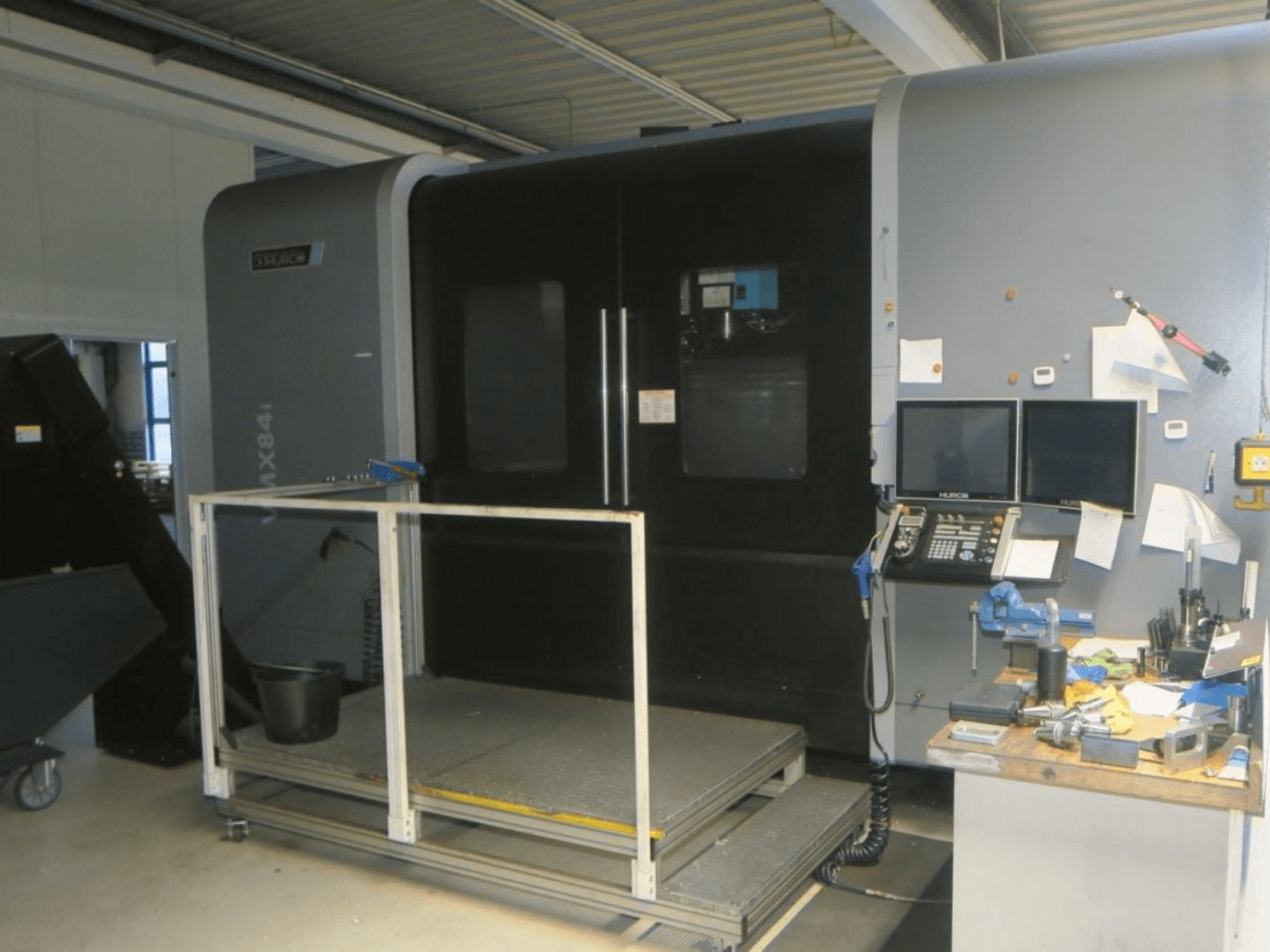 Hurco MX84 CNC-pink eesvaates, millel on kaks monitori, juhtpaneel ja tööriistade tööruum koos erinevate tööriistadega.