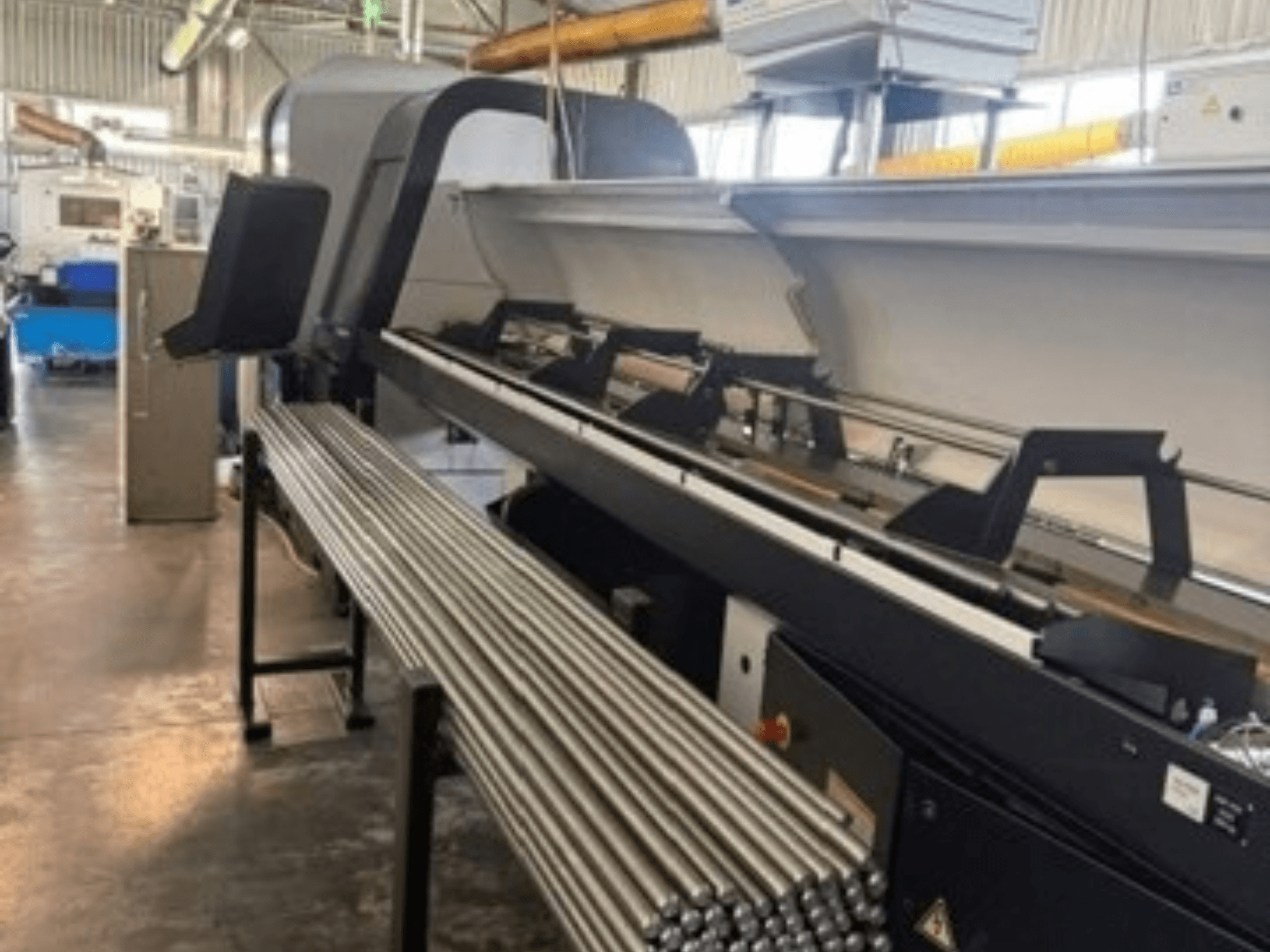 TORNOS EvoDECO 32 Šveitsi tüüpi treipinki esivaade, mille kõrval on rivistatud metallvardad, mis illustreerivad tööstuslikku töökeskkonda.