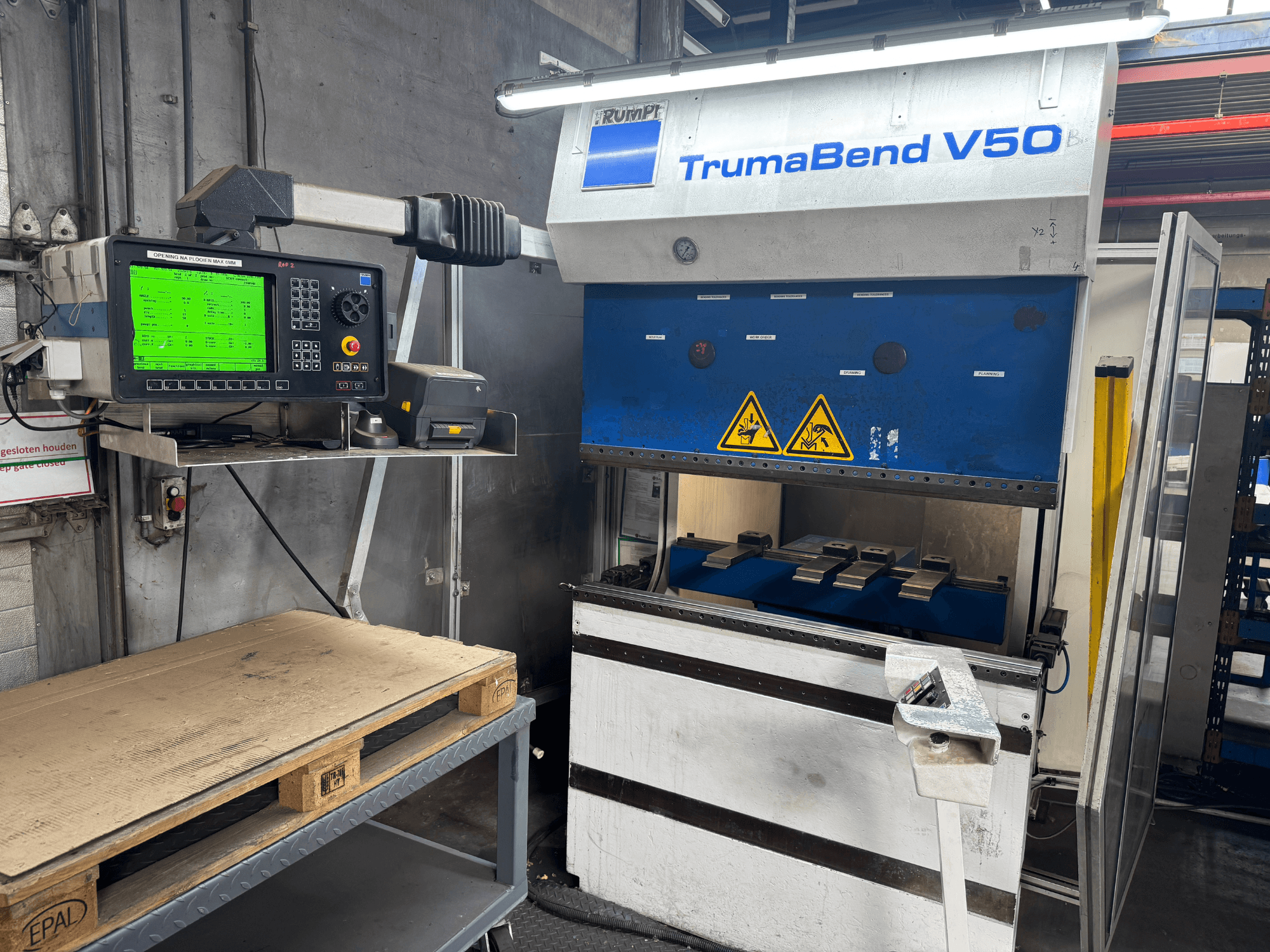 TRUMPF TrumaBend V50 pressipidur, esiplaanil, seadete ja ohutushoiatussiltidega juhtpaneel.