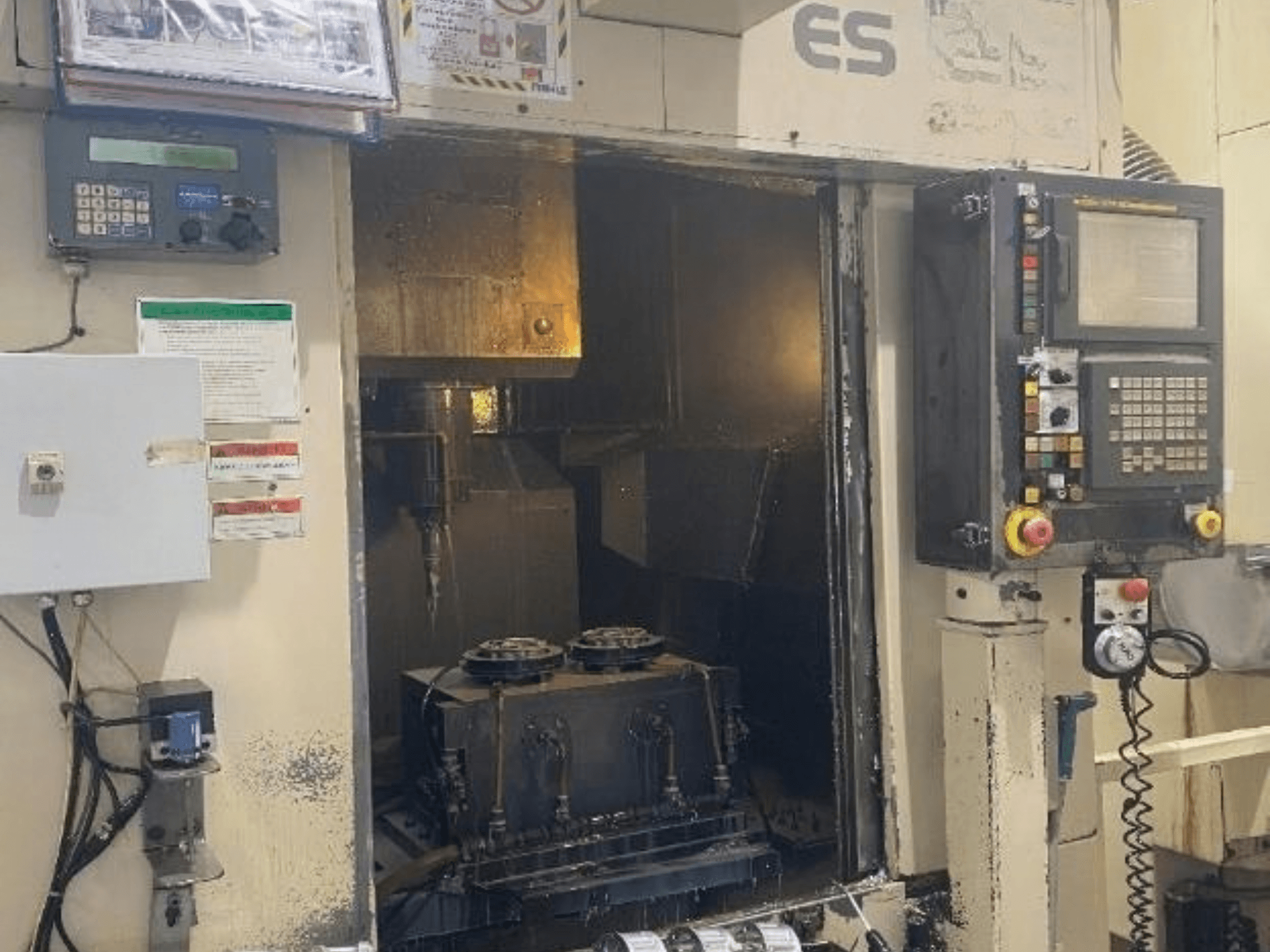 Enshu ES450 vertikaalse töötlemiskeskuse vaade eest, millel on näha juhtpaneelid, sisemine vaade ja tööriistade hoidmisala.