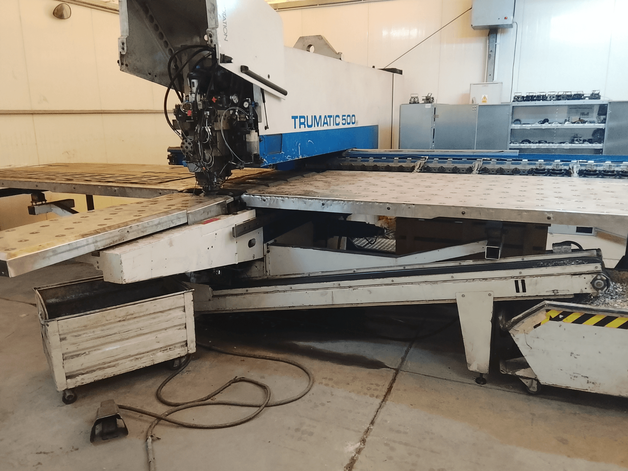 TRUMATIC 500 CNC-tööpink töökojas, külgvaates on näha lõikepää ja metalltöölaud koos eelpuuritud aukudega.