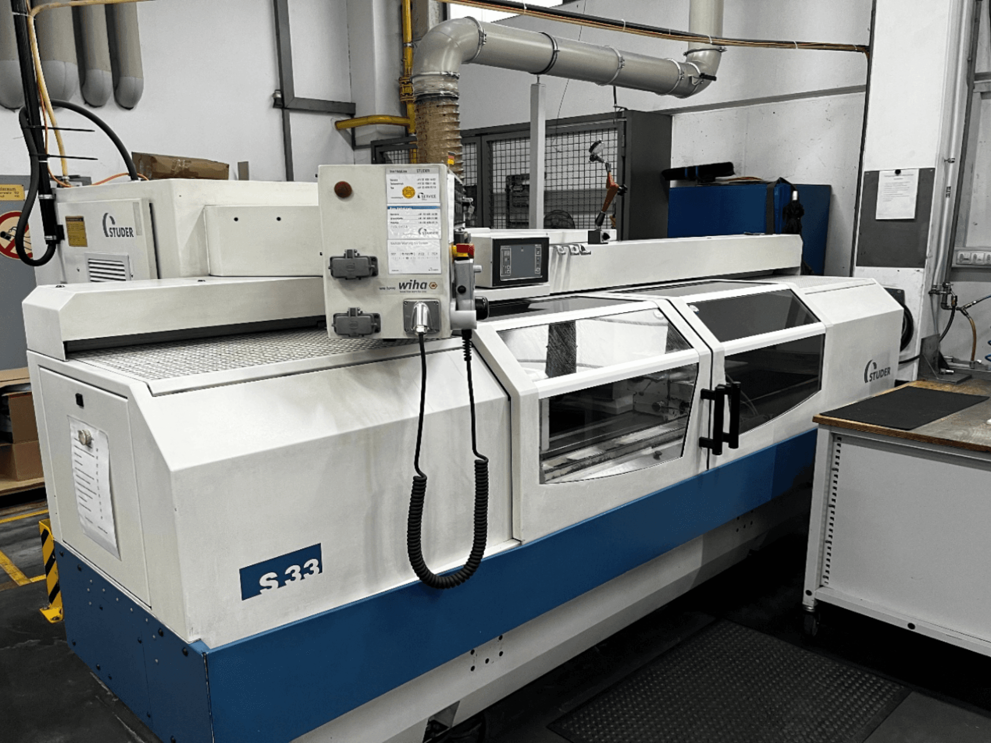 STUDER S33 CNC silindriline lihvimismasin, esivaade; juhtpaneel ja klaasist turvauksed. Tööstuslik seade.