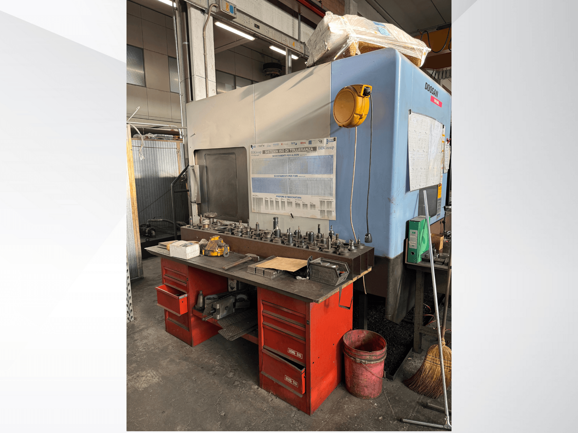 Doosan töötluskeskus punase töölaua ja ladustamise, tööriistade ja seadmete väljapanekuga, vaadatuna eestpoolt.