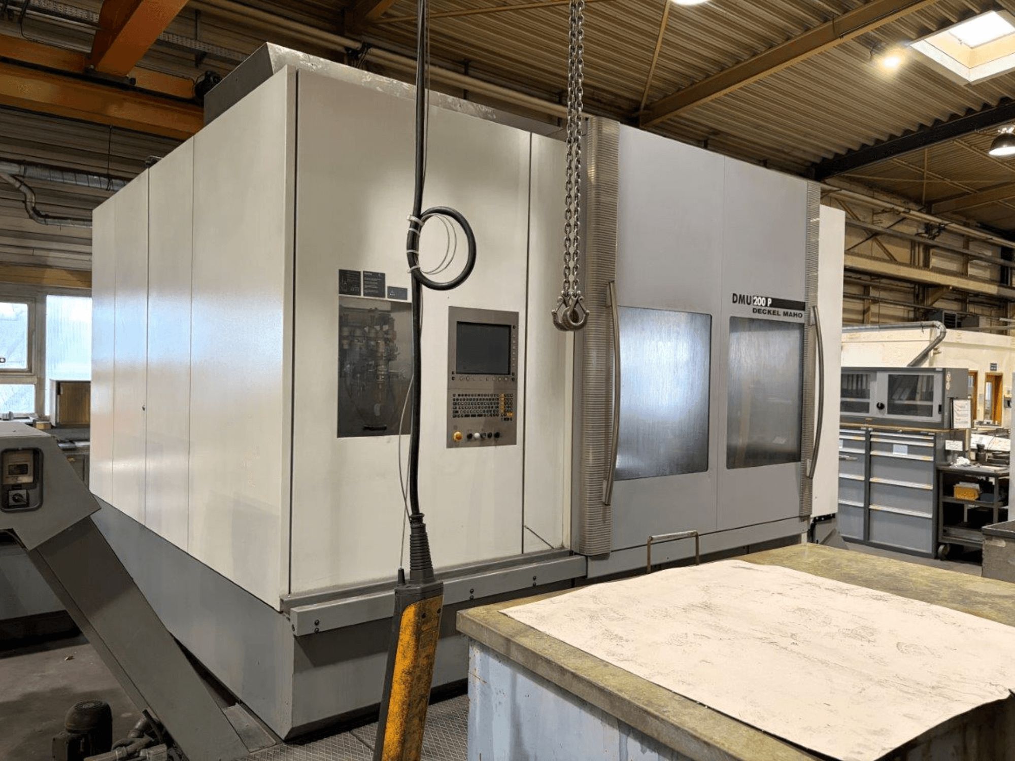 DMG MORI DMU 200 universaaltöötluskeskus töökojas, esiplaanil, kus on näidatud selle juhtpaneel ja välised omadused.