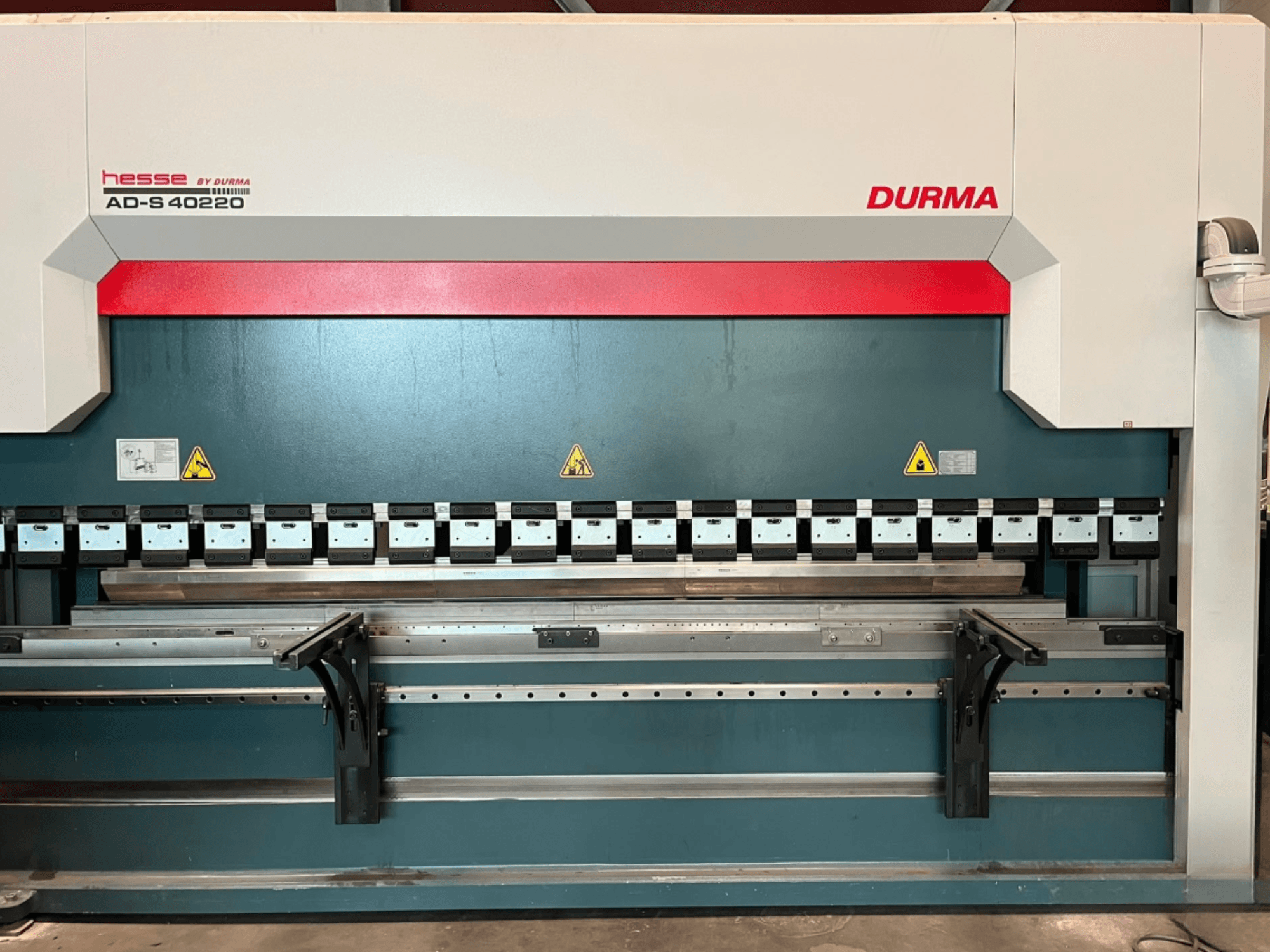 Durma AD-S 40220 painutuspress, vaade eest, millel on mitmed painutusriistad ja ohutusmärgised.