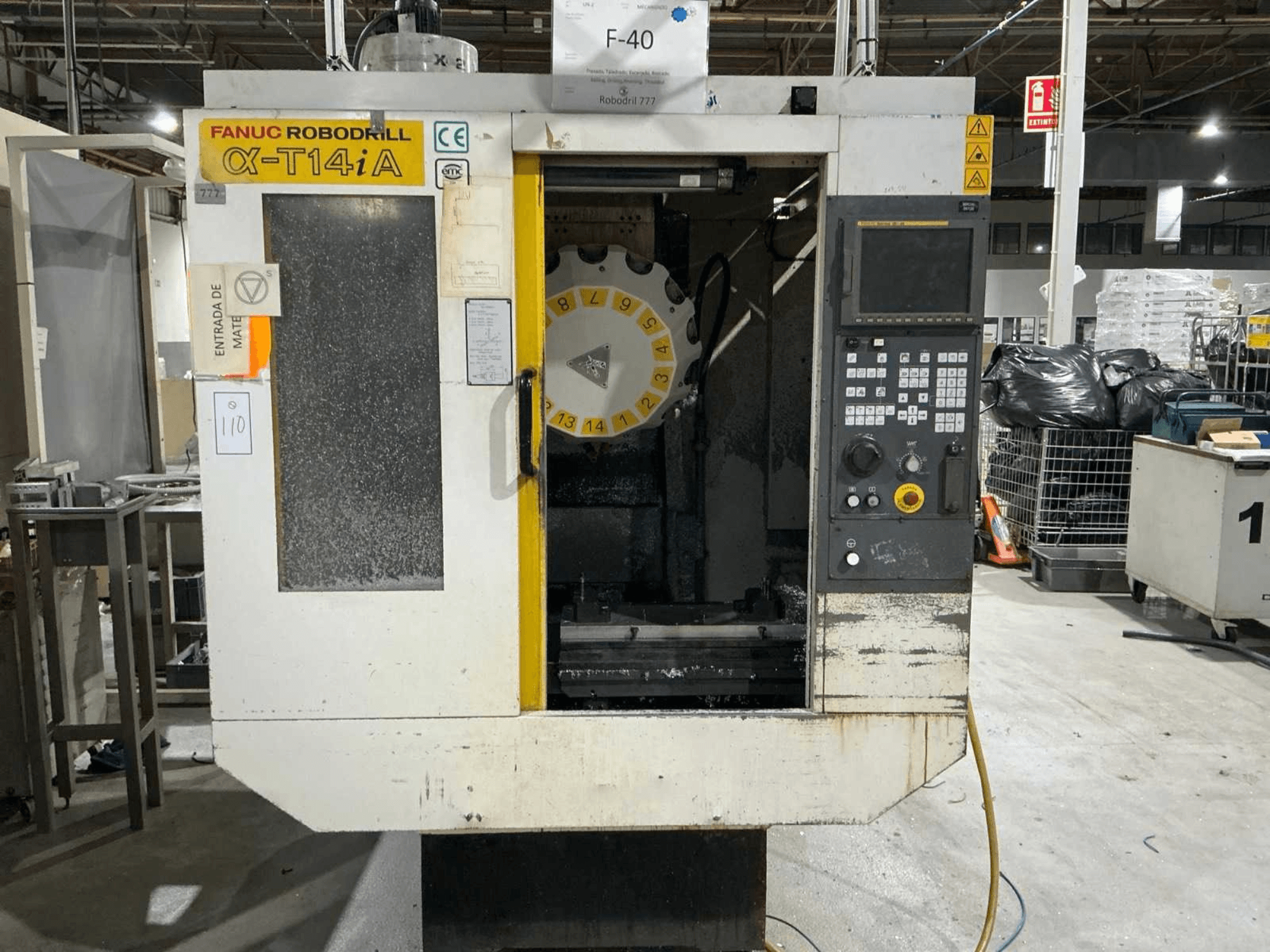 FANUC ROBODRILL α-T14iB vertikaalne töötlemiskeskus, esiplaanil on juhtpaneel ja tööriistakarussell.