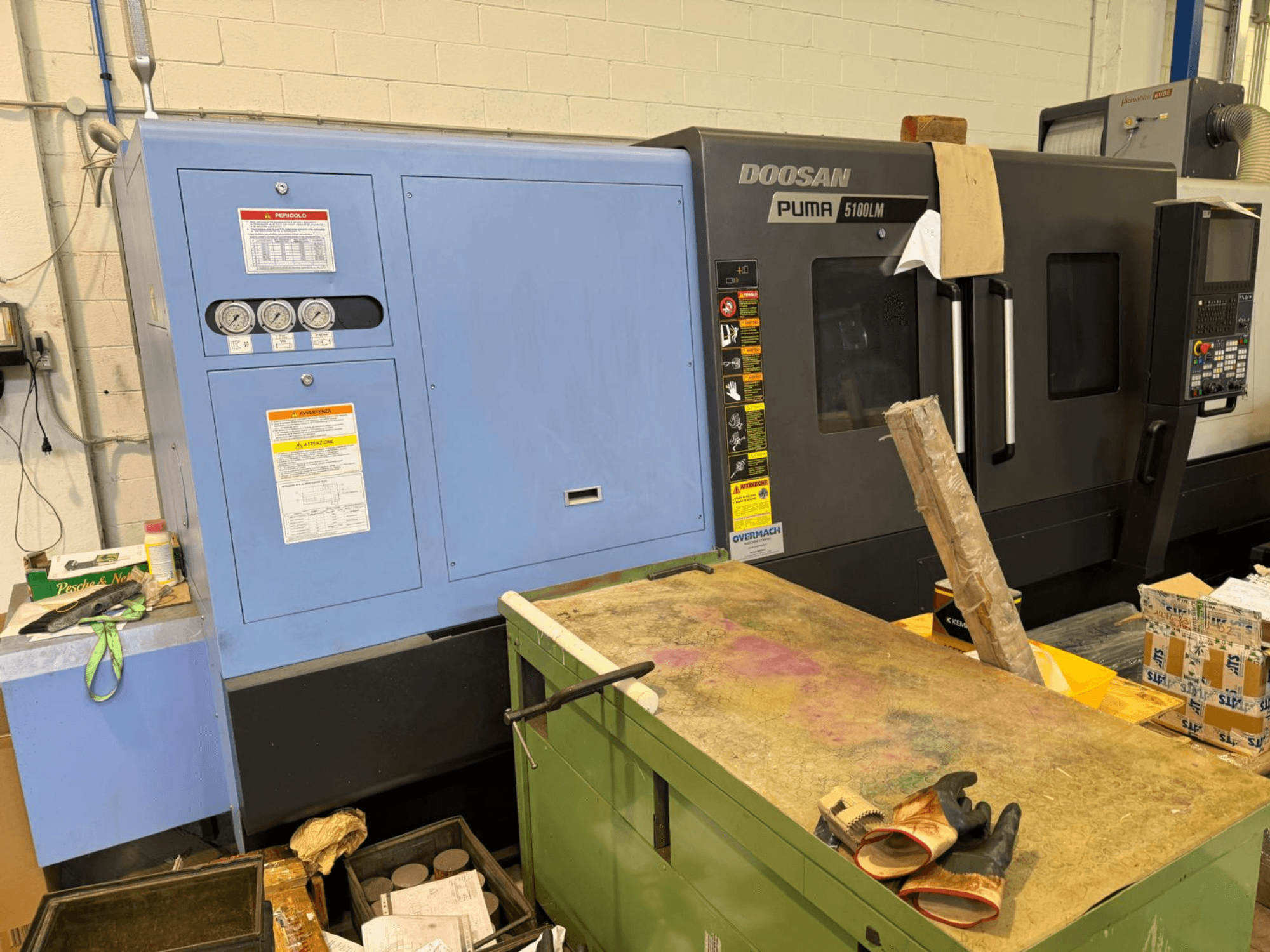 Doosan Puma 5100LM CNC masin ja juhtpaneel, külgvaade. Sinisel juhtseadmel nähtavad näidikud ja hoiatussildid.