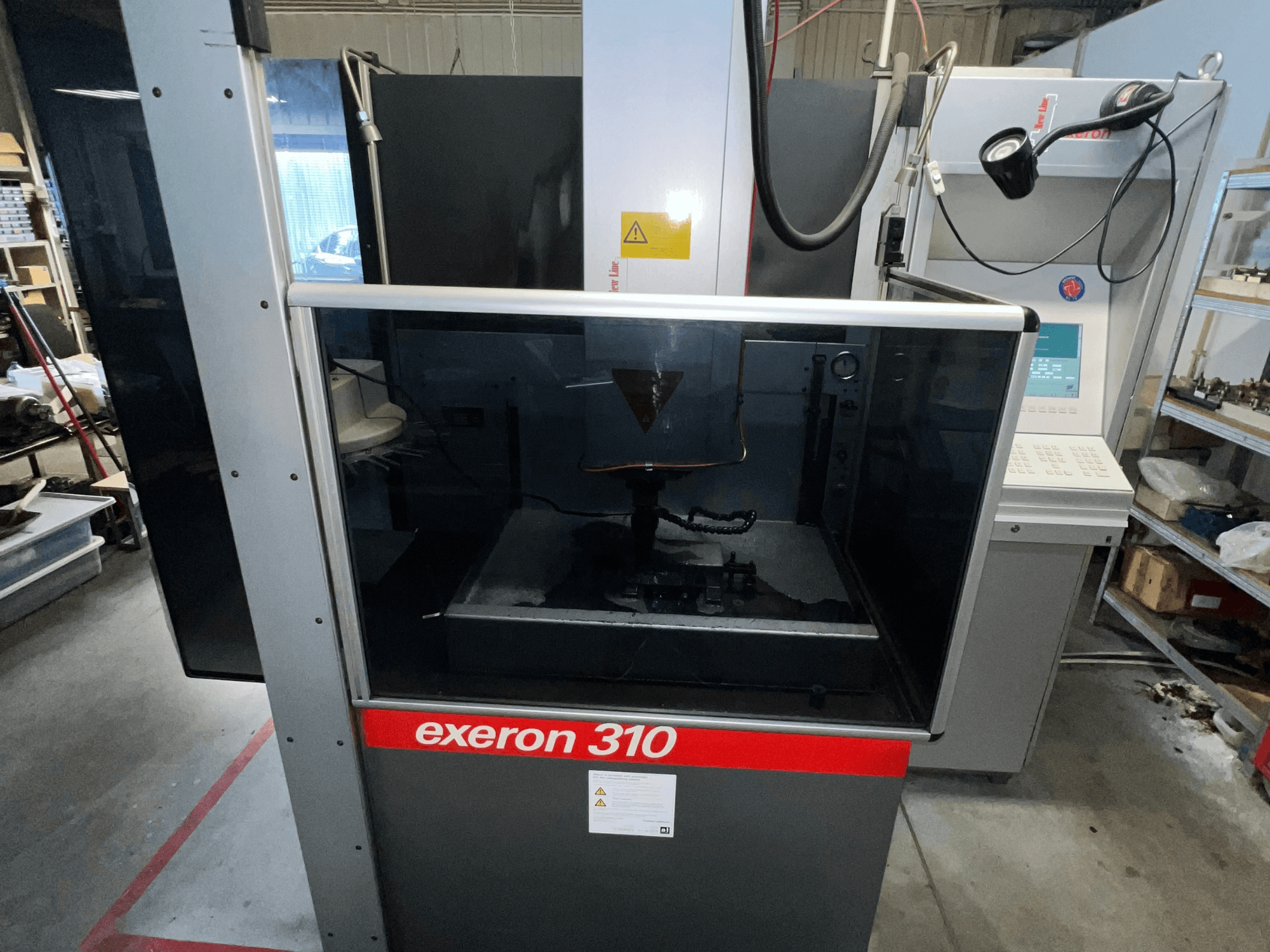 Exeron 310 masina esivaade, kus on näha klaasist kamber ja juhtpaneel koos tööjaama riiulitega.