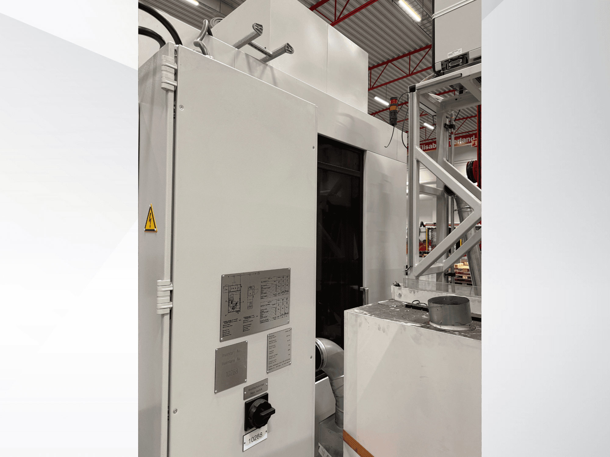 Valge tööstusliku masina külgvaade koos juhtpaneeli ja hoiatussildiga, mis on osa automatiseeritud süsteemist.