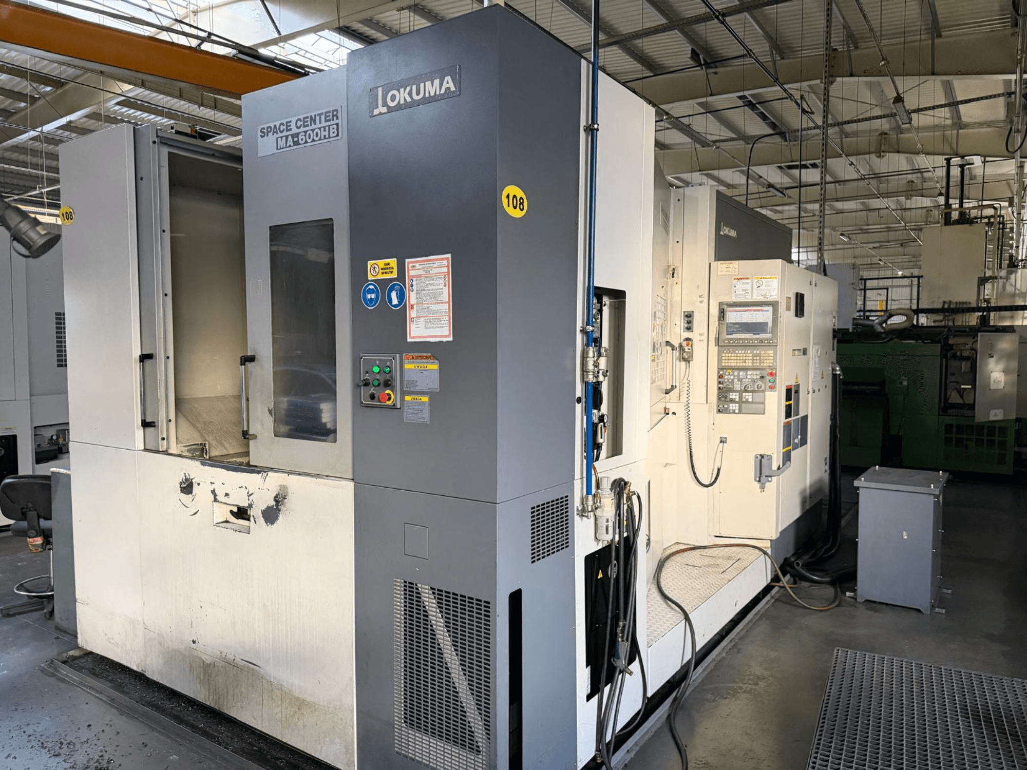 Okuma MA-600 HB horisontaalne töötlemiskeskus, esiplaan, kus on näha juhtpaneel ja lõikepind koos nähtavate kulumisjälgedega.