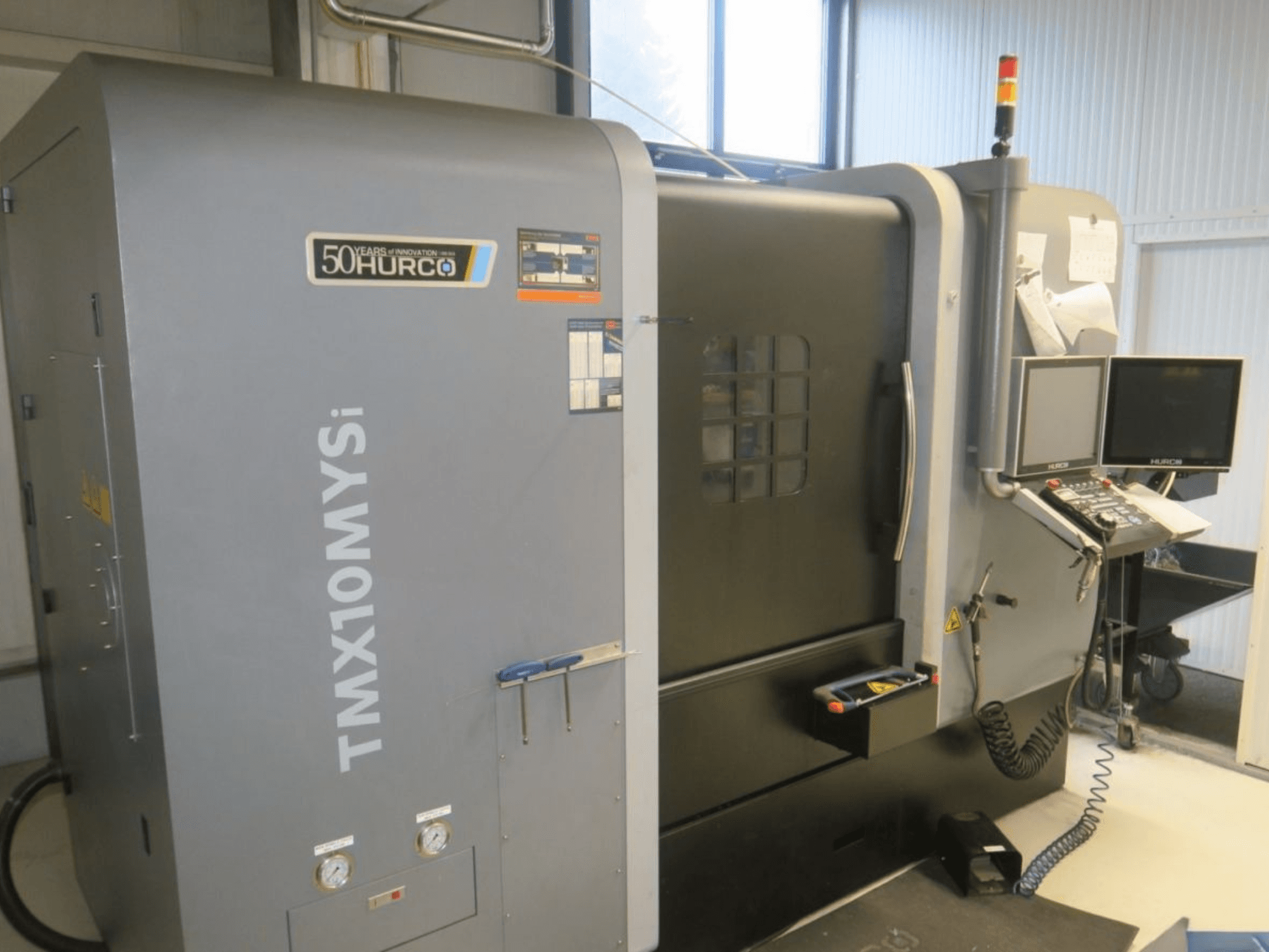 Hurco TMX10MYSi CNC-tööpingi külgvaates; näidatakse juhtpaneeli, avariituled ja näidikud.