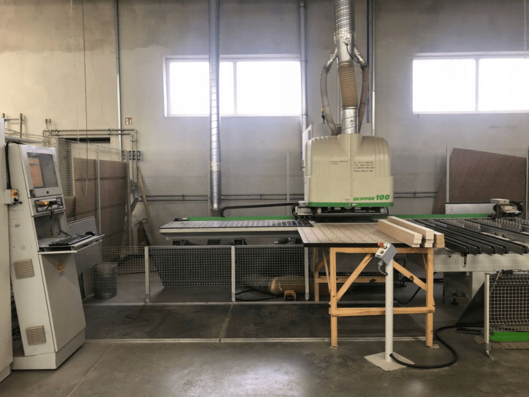 Töökojas asuv BIESSE SKIPPER 100 CNC-töötlemiskeskus; esivaates on näha masin koos juhtpaneeliga ja laual olev puit.
