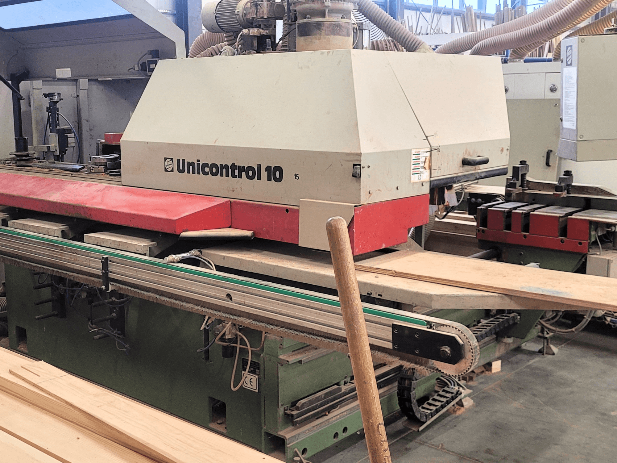 WEINIG/DIMTERi CNC töötlemiskeskus Unicontrol 10, esiplaanil puidust laudade ja seadmetega töökojas.
