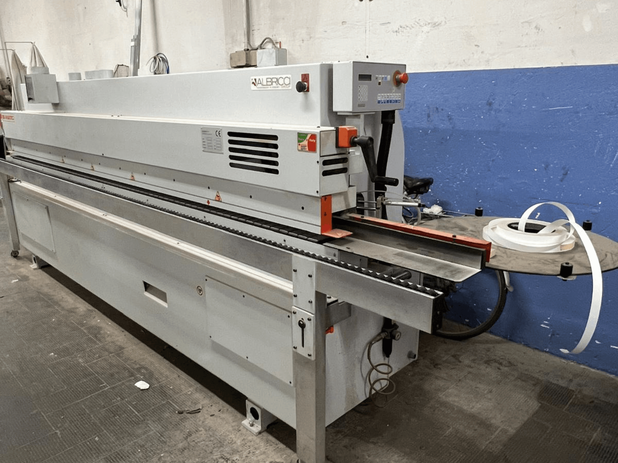 ALBRICO servapaigaldusmasin esivaates, millel on pikk konveierilint ja kinnitatud kleeplindirull.