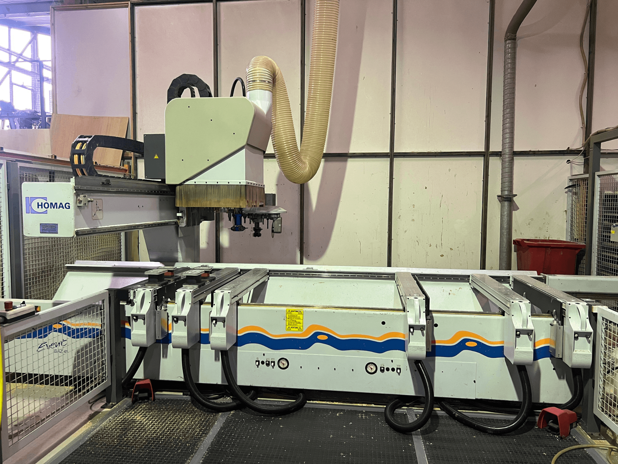 HOMAG BIZ 4 CNC-tööpink töökojas; esiplaanil on näha tolmueemaldussüsteem ja juhtpaneel koos kaablitega.