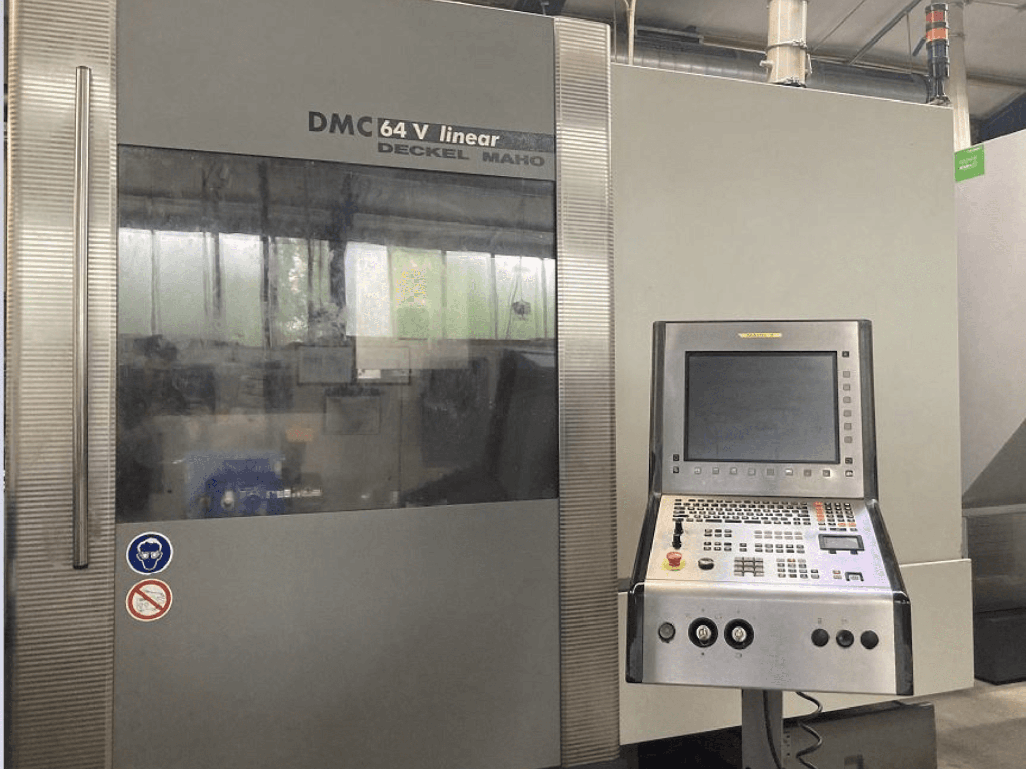 DMG DECKEL MAHO DMC 64V lineaarne vertikaalne töötlemiskeskus, esiplaanil on juhtpaneel ja ekraan.