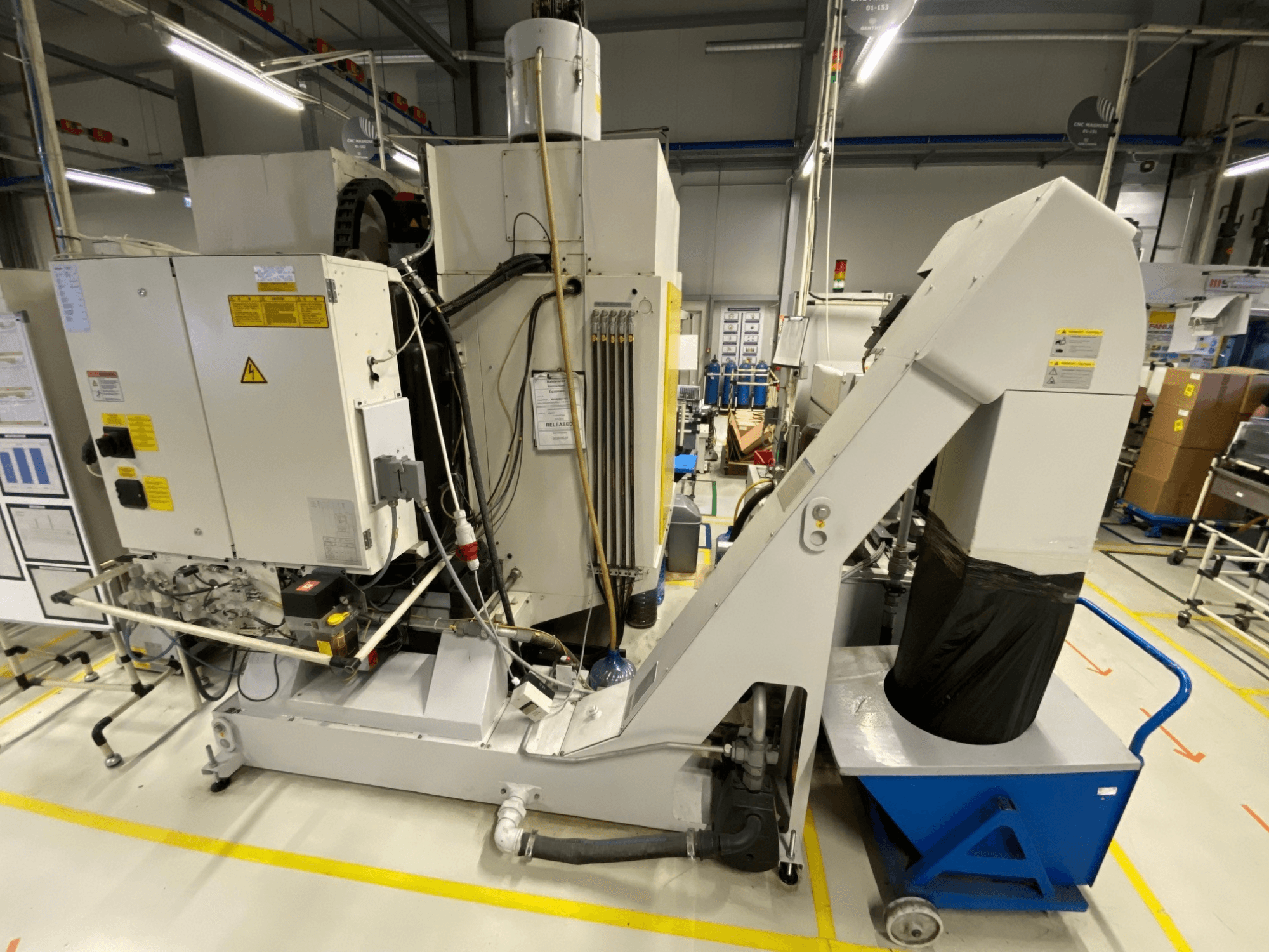 FANUC ROBODRILL α-D21LiB vertikaalse töötlemiskeskuse esivaade, millel on näha elektrilised komponendid ja väljundkanal.