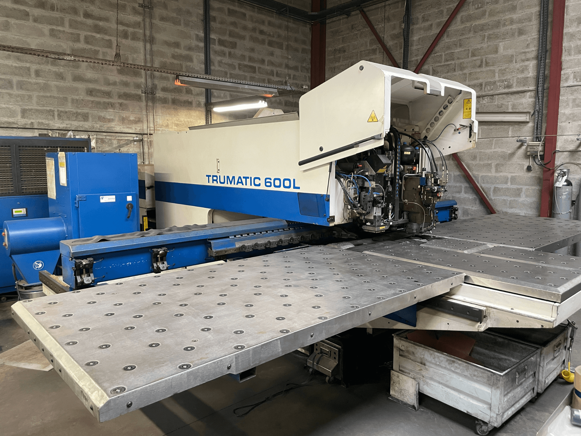 CO2-laserlõikepink TRUMPF TRUMATIC TC 600L, esiplaanil on nähtav metallilõikelaud ja juhtpaneel.