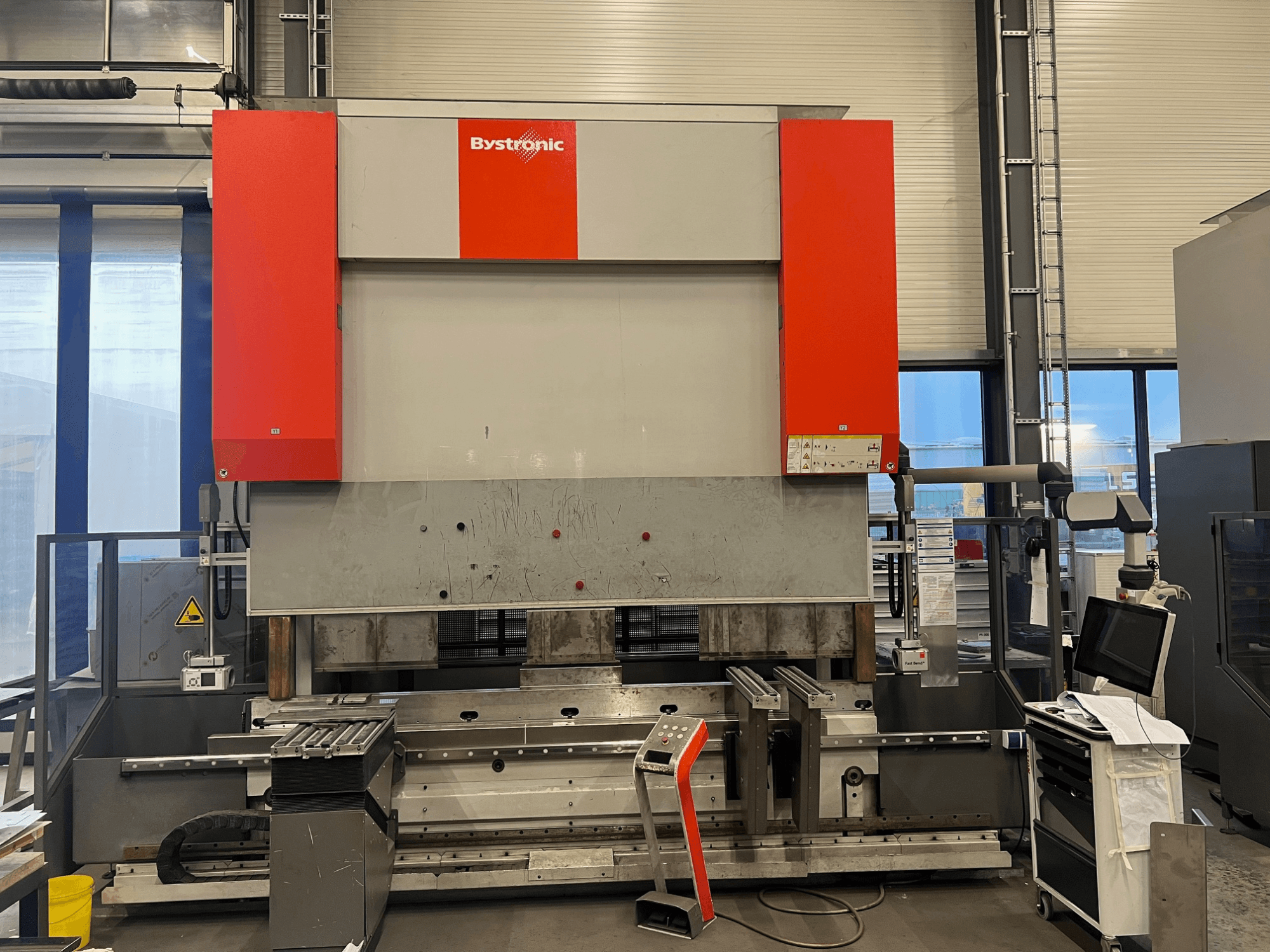 Bystronici lehtmetalli painutusmasin esiplaanil, millel on elegantne disain, juhtpaneel ja turvaelemendid.