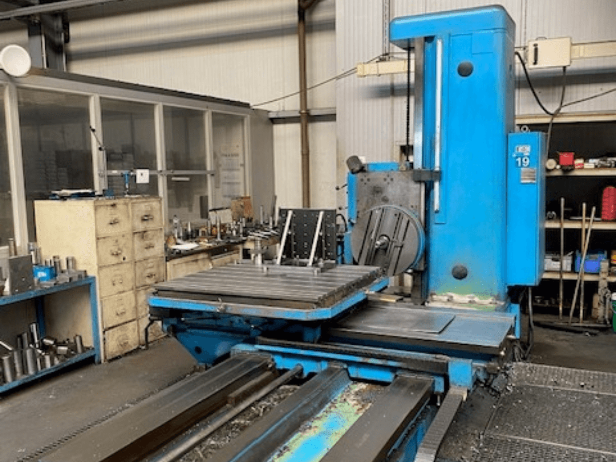 Sinine freespink eesvaates, mudel nr 19, töökoja põrandal, tagaplaanil tööriistad ja hoiukapp.