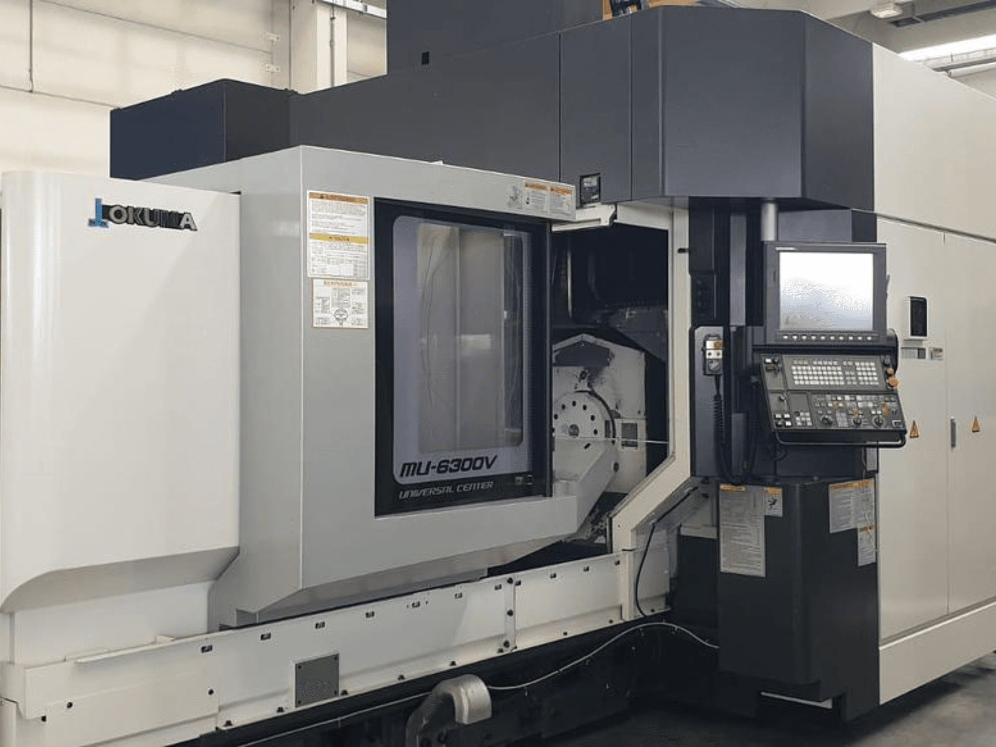 Okuma MU 6300 V vertikaalne töötluskeskus, esiplaan, kus on näidatud juhtpaneel ja töötlusala üksikasjad.