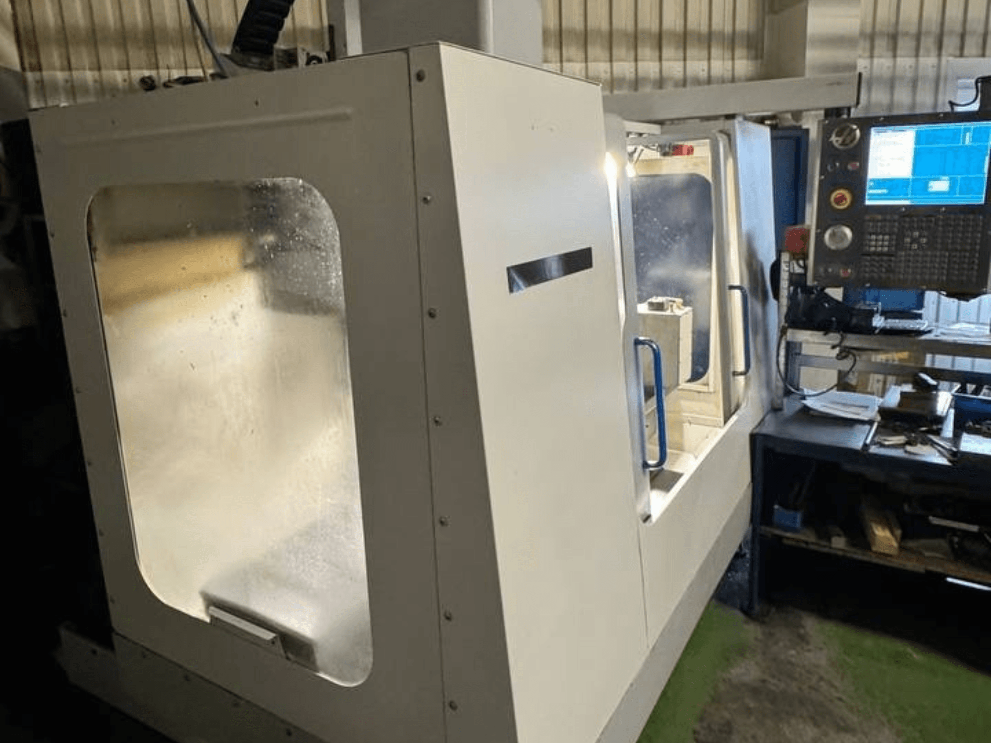HAAS VCE 750 vertikaalne töötlemiskeskus külgvaates, millel on juhtpaneel ja selge turvakate.