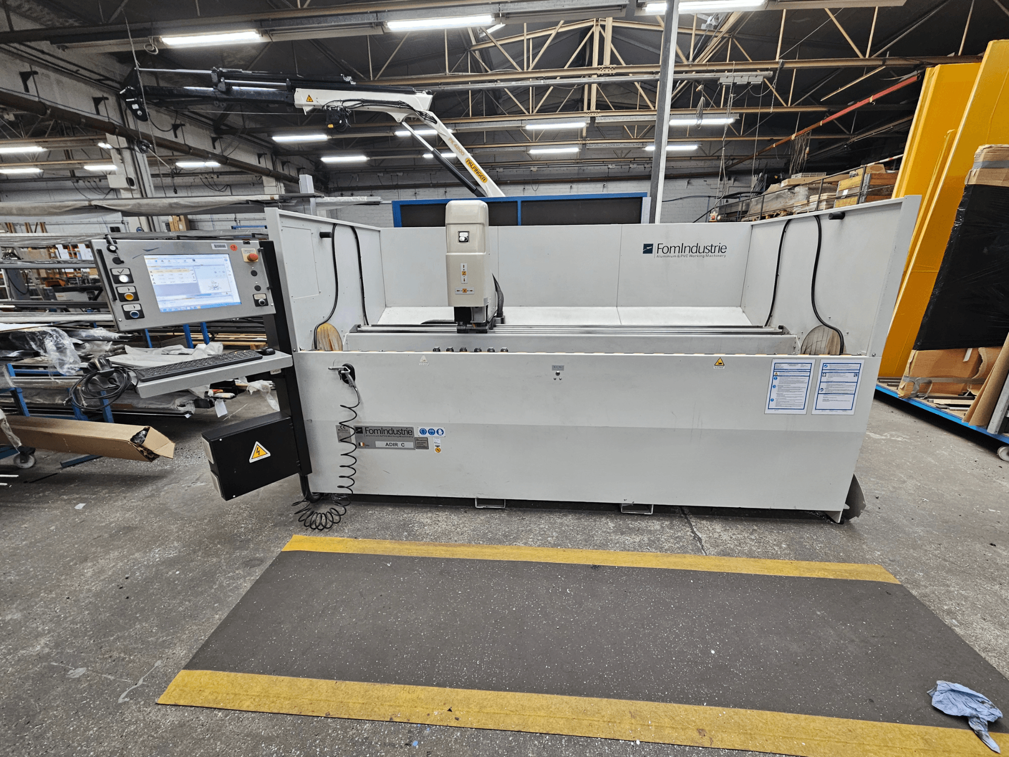 FomIndustrie ADIR C vertikaalne töötluskeskus töökojas, esiplaanil on juhtpaneel ja masina üksikasjad.