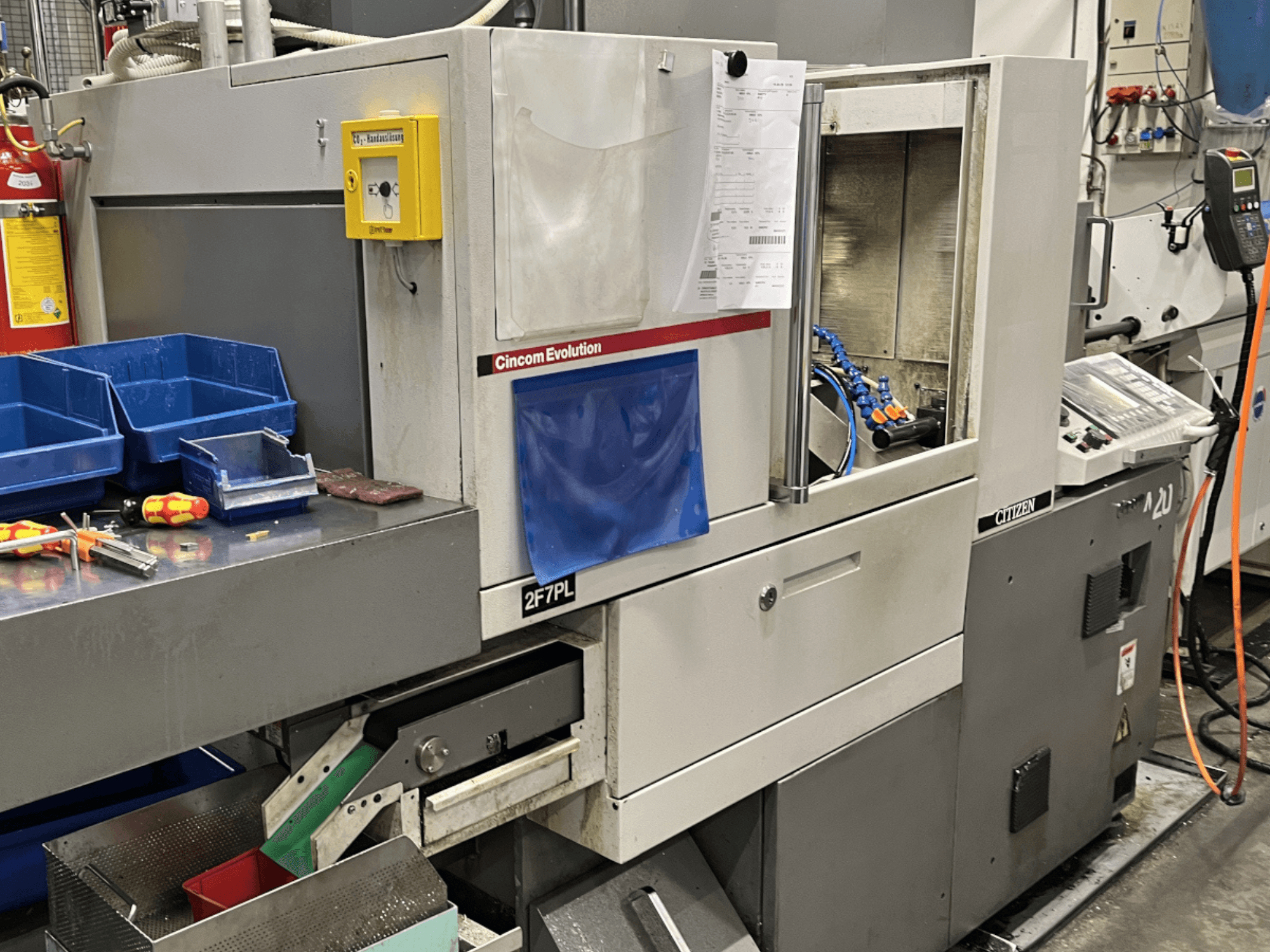 Cincom Evolution 2F7PL töötluskeskus, esiplaanil; juhtseadmed, tööriistakastid ja üksikasjalik juhtpaneel.