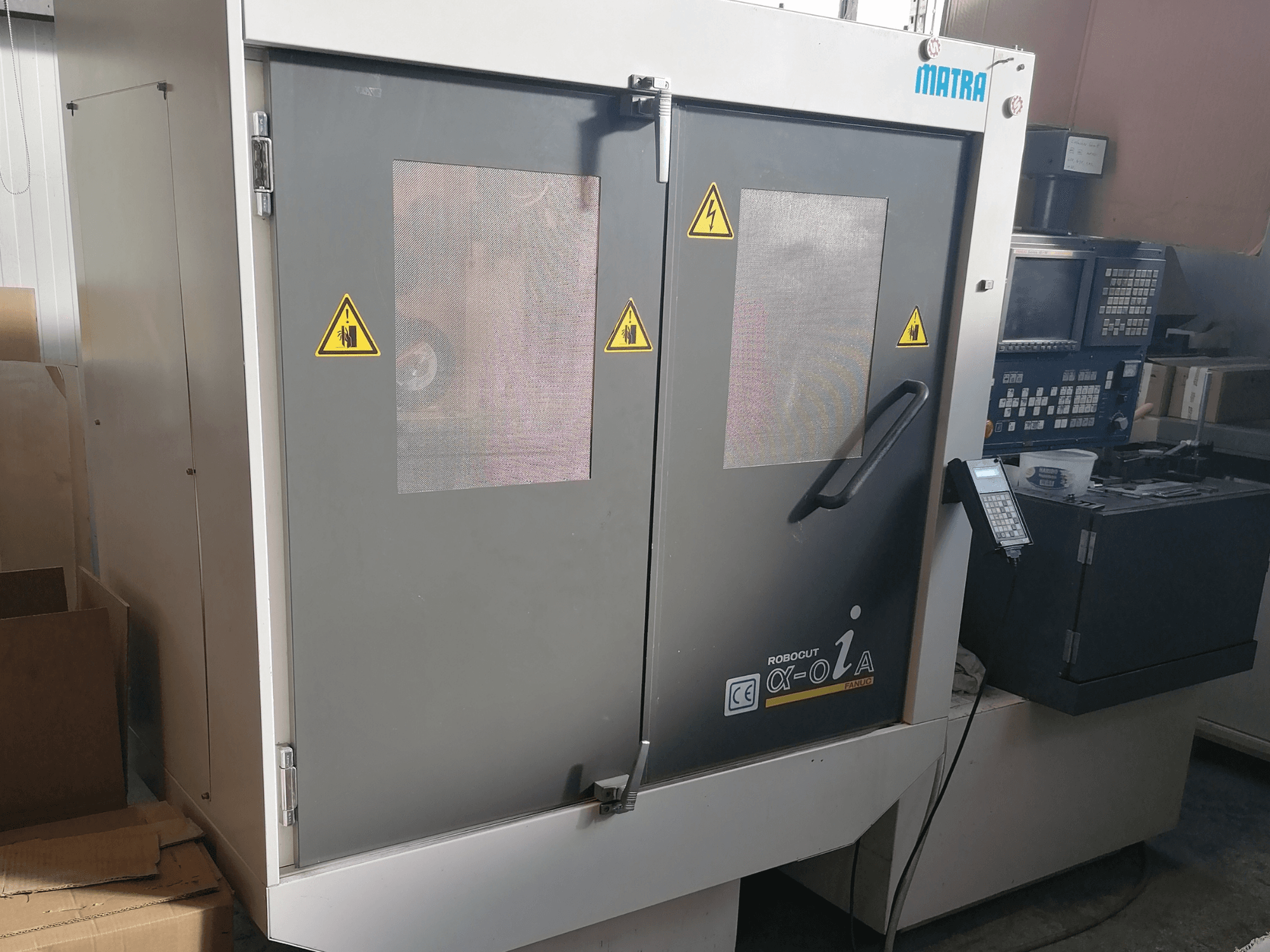 Matra Robocut α-oZα masin, esiplaanil on näha ohutushoiatused, juhtpaneel ja kaks ukseklaasi.