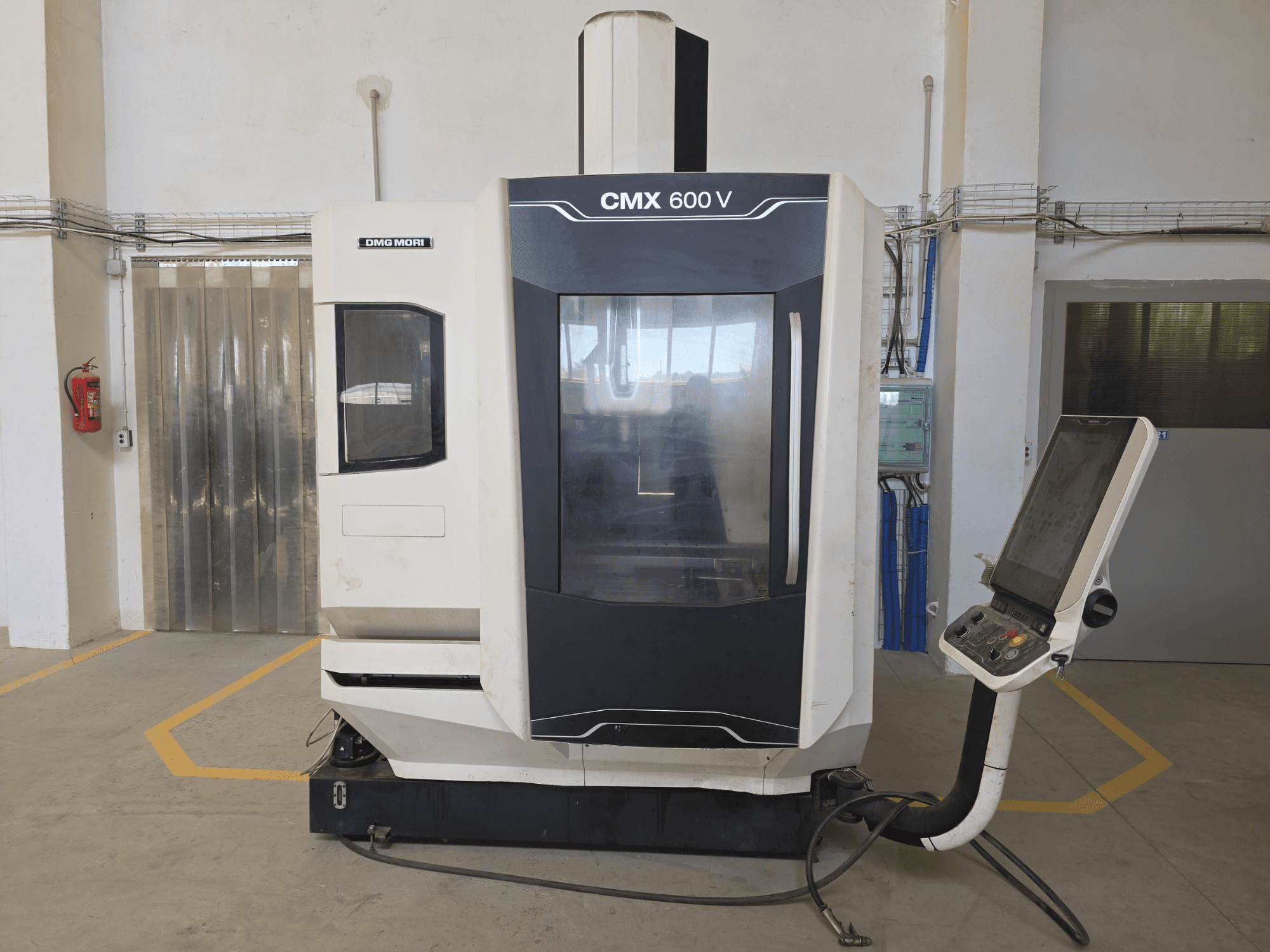 DMG MORI CMX 600 V vertikaalne töötluskeskus, esiplaanil, kus näidatakse juhtpaneeli ja suurt läbipaistvat akent.
