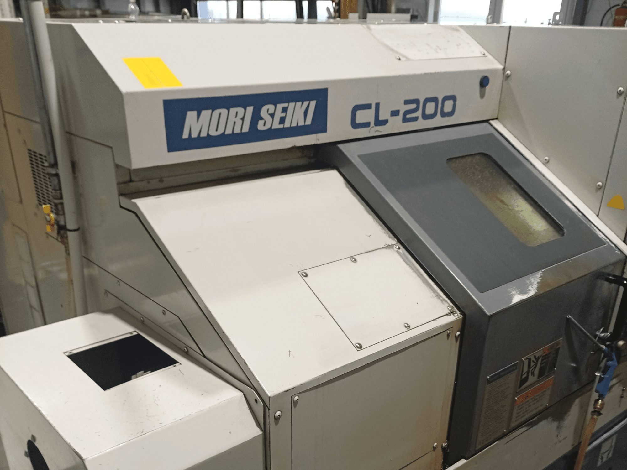 DMG Mori Seiki CL-200B horisontaalne treipink, esiplaanil on näidatud juhtpaneel ja jahutusvedeliku akna üksikasjad.