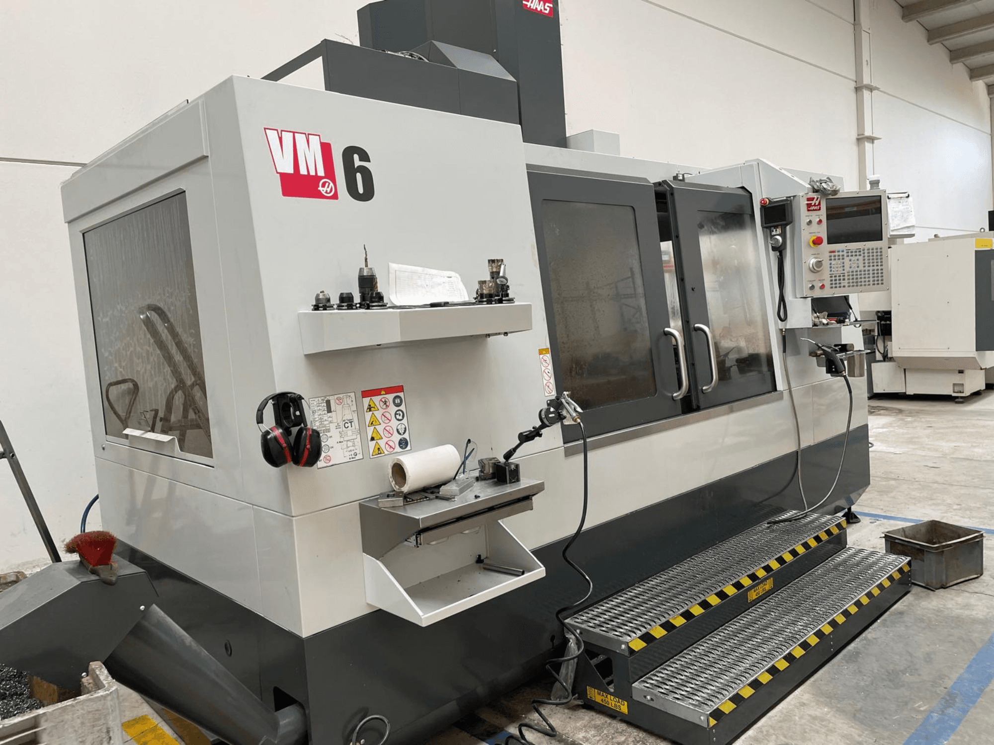 Haas VM-6 vertikaalne töötluskeskus, esiplaan, kus on näidatud juhtpaneel, tööriistahoidikud ja ohutusseadmed.