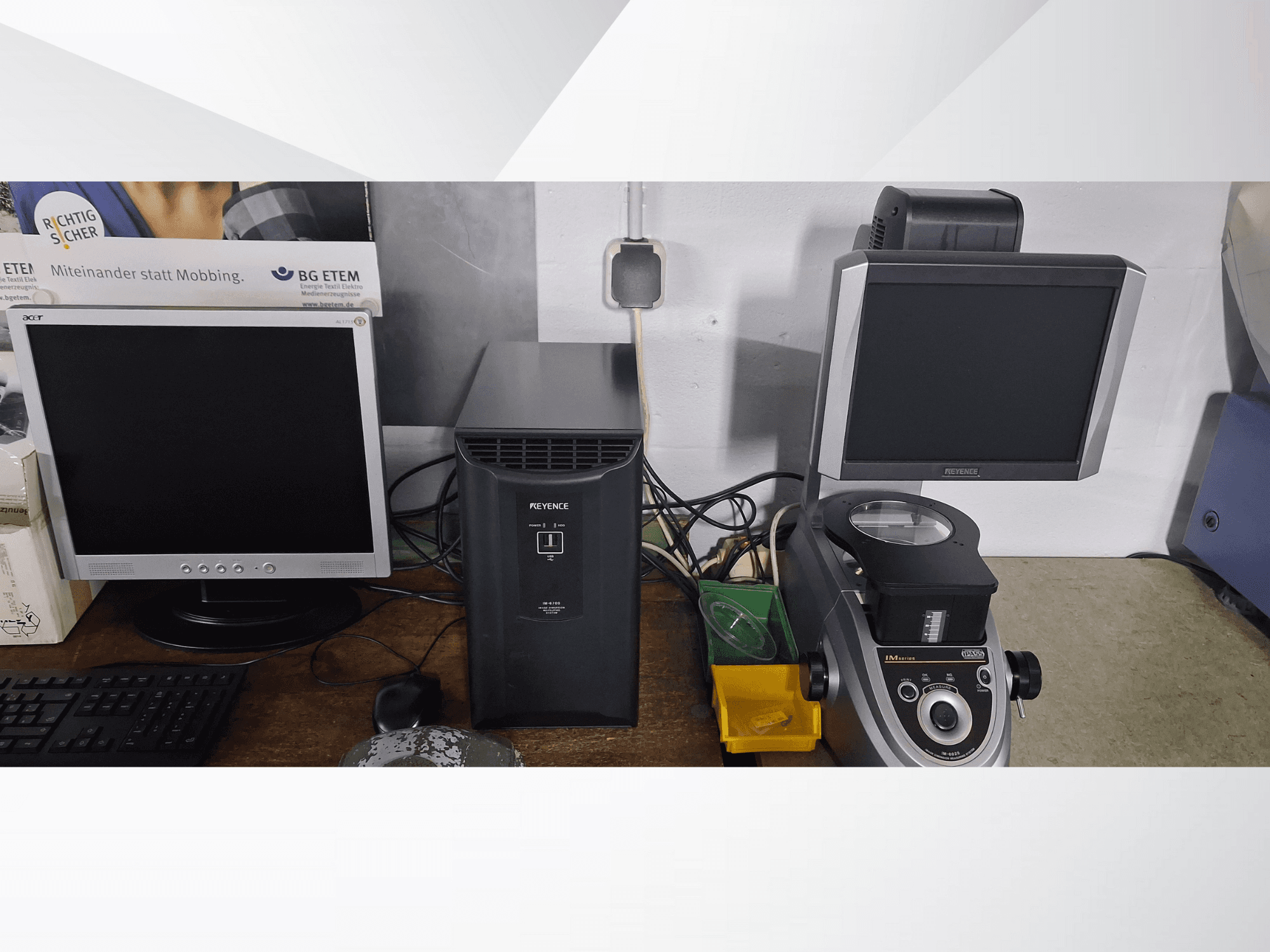 Kaks arvutimonitori, üks Acer ja üks Keyence, musta seadme ja mikroskoobi kõrval, esiplaanilt vaadatuna.