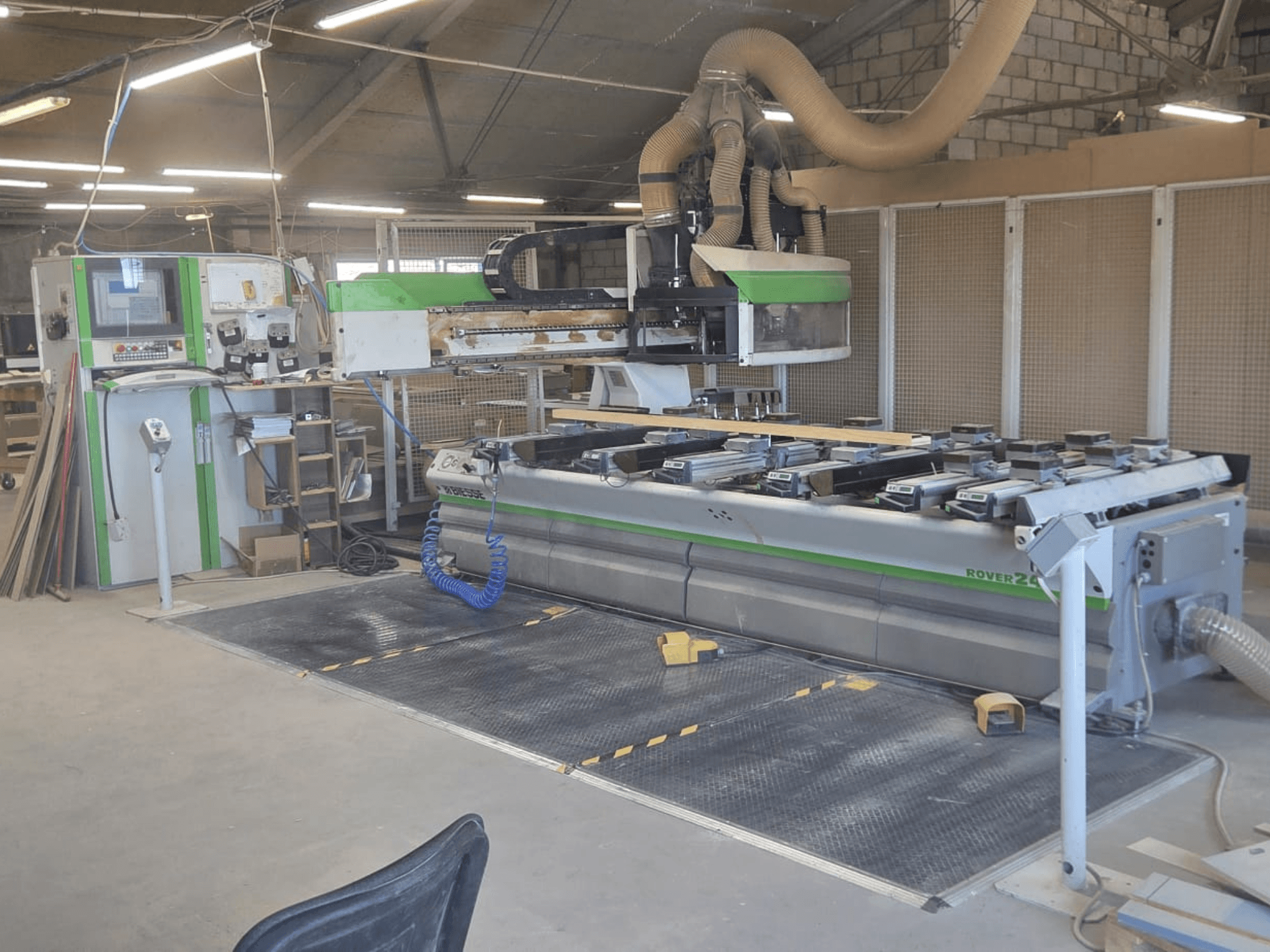 CNC töötlemiskeskus BIESSE Rover 24S töökojas, kus on juhtpaneel ja suur tööpind puidutükkidega.