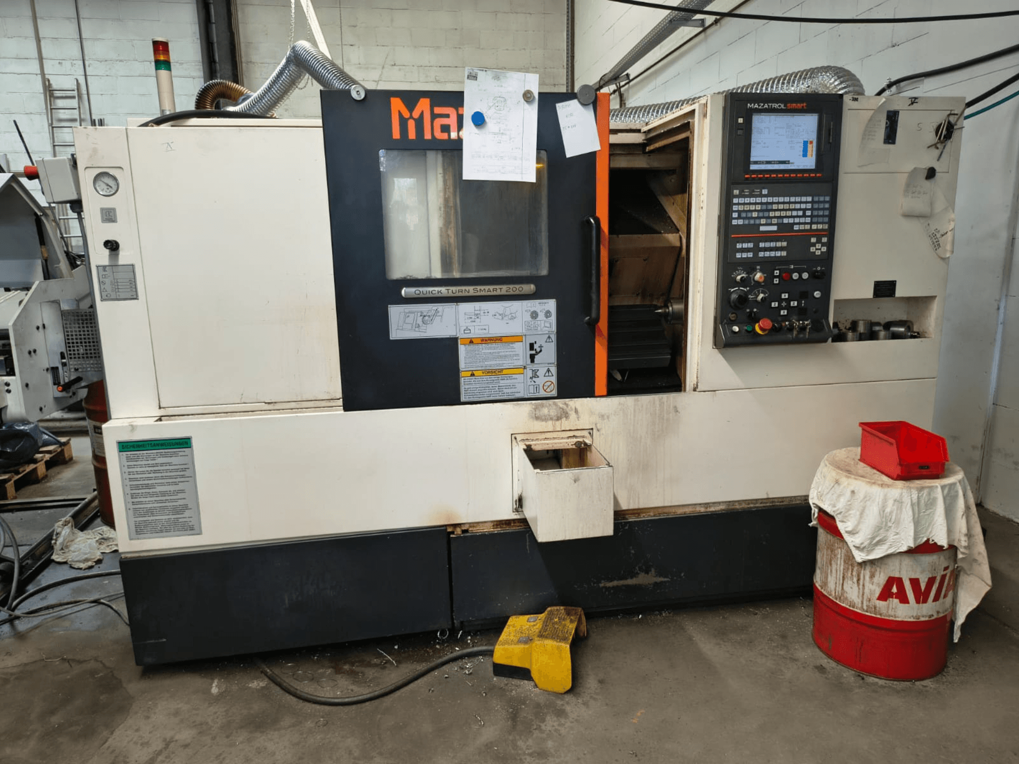 Mazak Quick Turn Smart 200, horisontaalne treipink, vaade eest, kus on näha juhtpaneel, jahutusvedeliku paak ja märgistused.