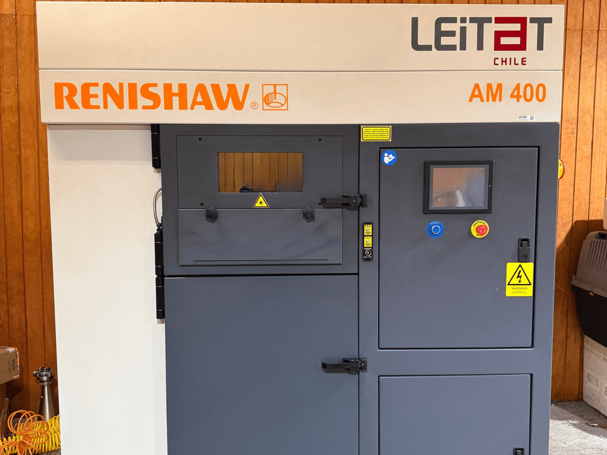 RENISHAW AM400 metallist 3D-printeri esivaade, millel on näha juhtpaneel, hoiatussildid ja hooldusluuk.