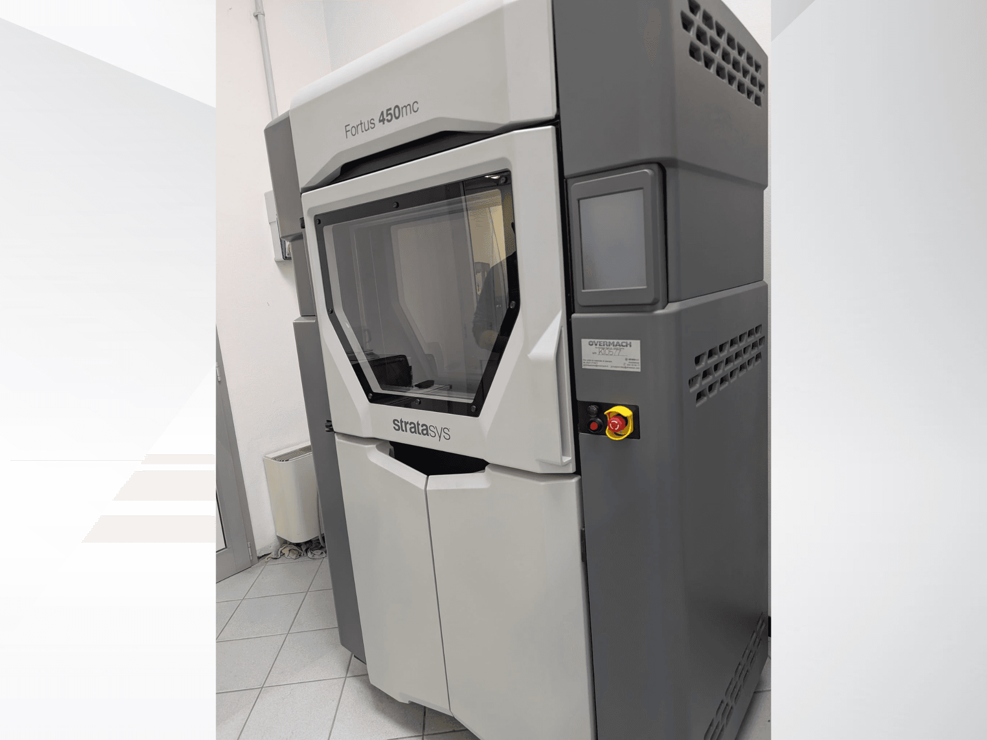 Plastikust 3D-printer Fortus 450mc külgvaates, millel on läbipaistev esipaneel ja juhtnupud küljel.