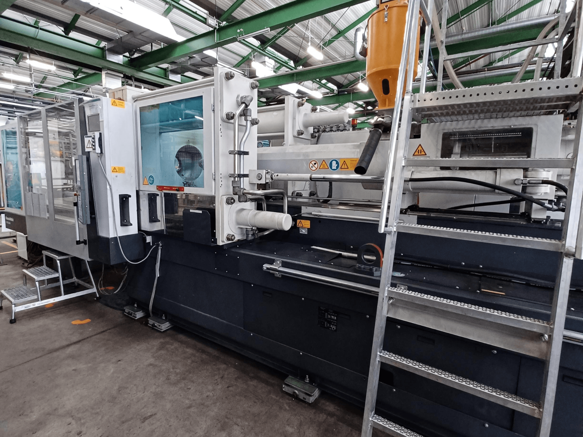 Tööstuslik survevalu masin, millel on selge esivaade, kus on näha kaubamärgi märgistus, juhtpaneel ja materjalipunker.