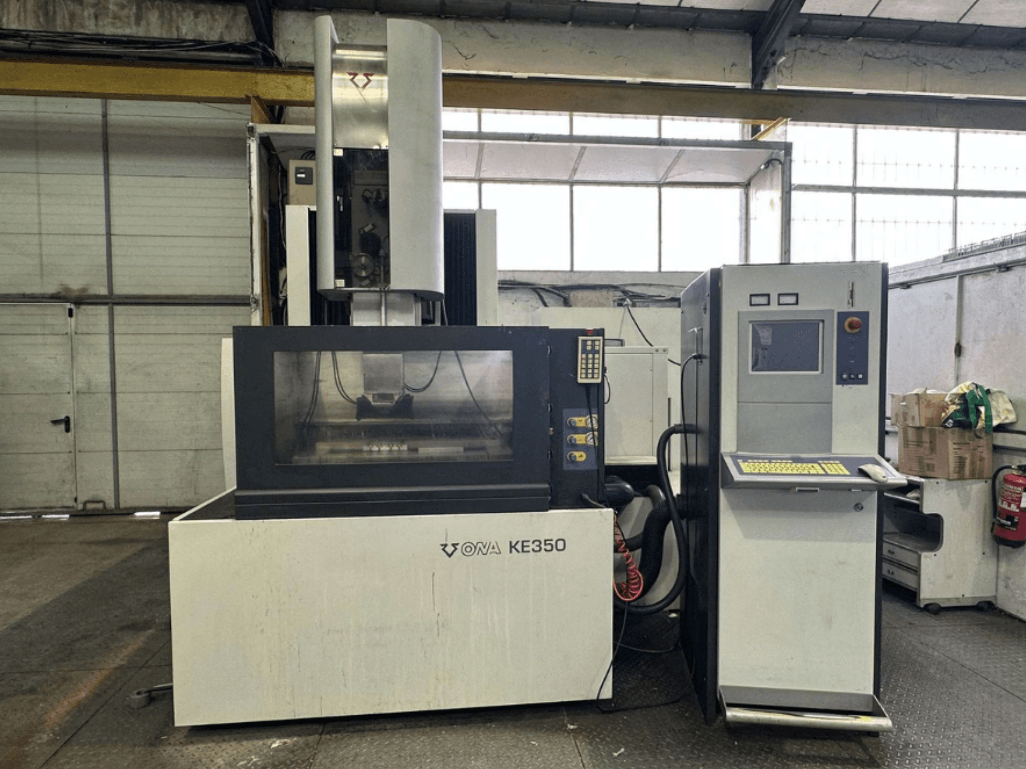 Tööstuslikus keskkonnas asuva ONA KE350 CNC-pingi esiosa koos juhtpaneeli, ekraani ja erinevate nuppudega.