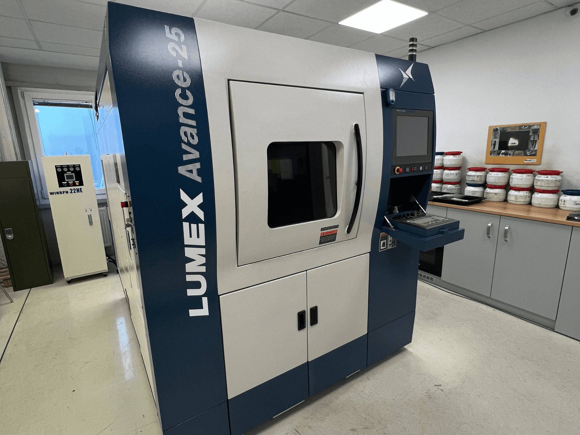 LUMEX Avance-25 3D-printer laboris, esiplaanil. Juhtpaneel koos ekraani ja nuppudega, taustal seadmed.