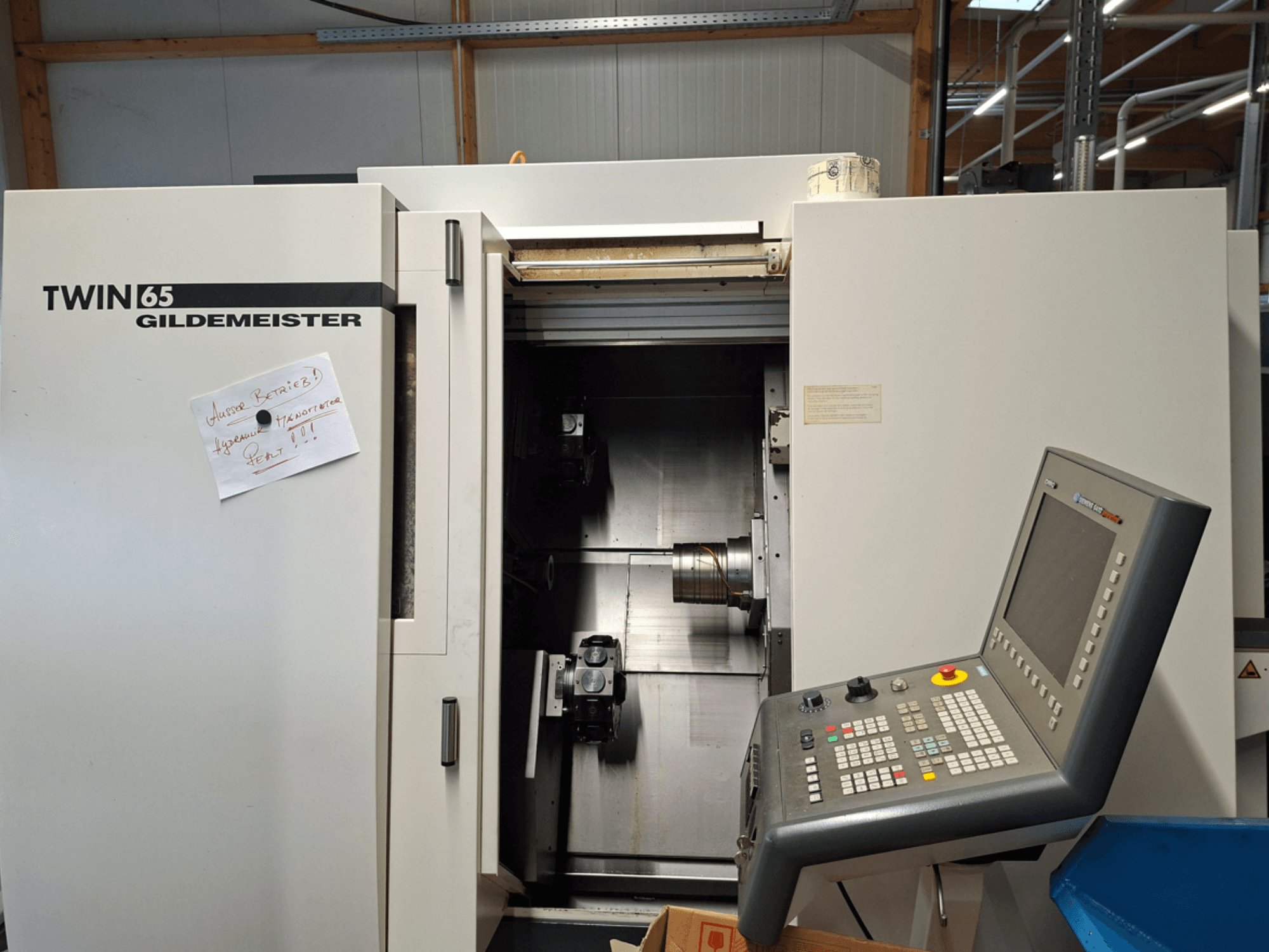 Gildemeister TWIN 65 CNC-teenindusega treipink, esiplaanil on juhtpaneel ja osaliselt avatud kamber koos nähtavate masinatega.